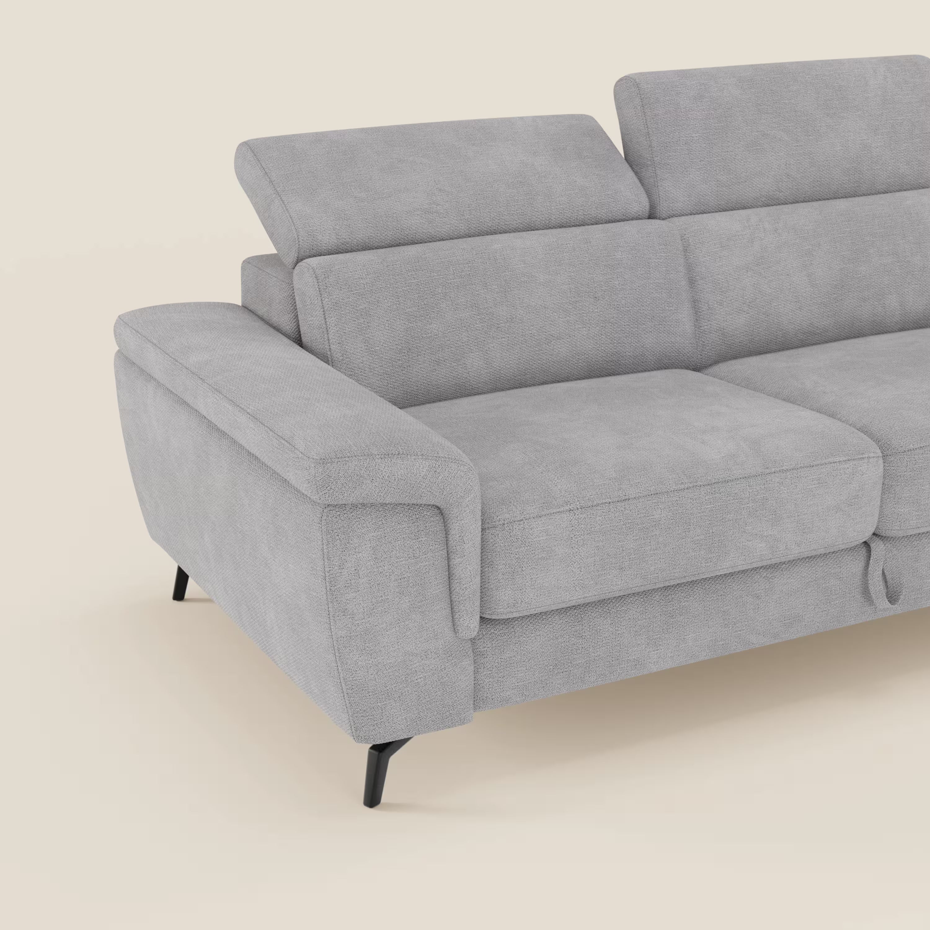 L'Estro Divano 3 posti con pouf estraibile di Divani.Store, in tessuto impermeabile T14 grigio chiaro e poggiatesta reclinabile, è visibile solo in parte su sfondo beige chiaro.