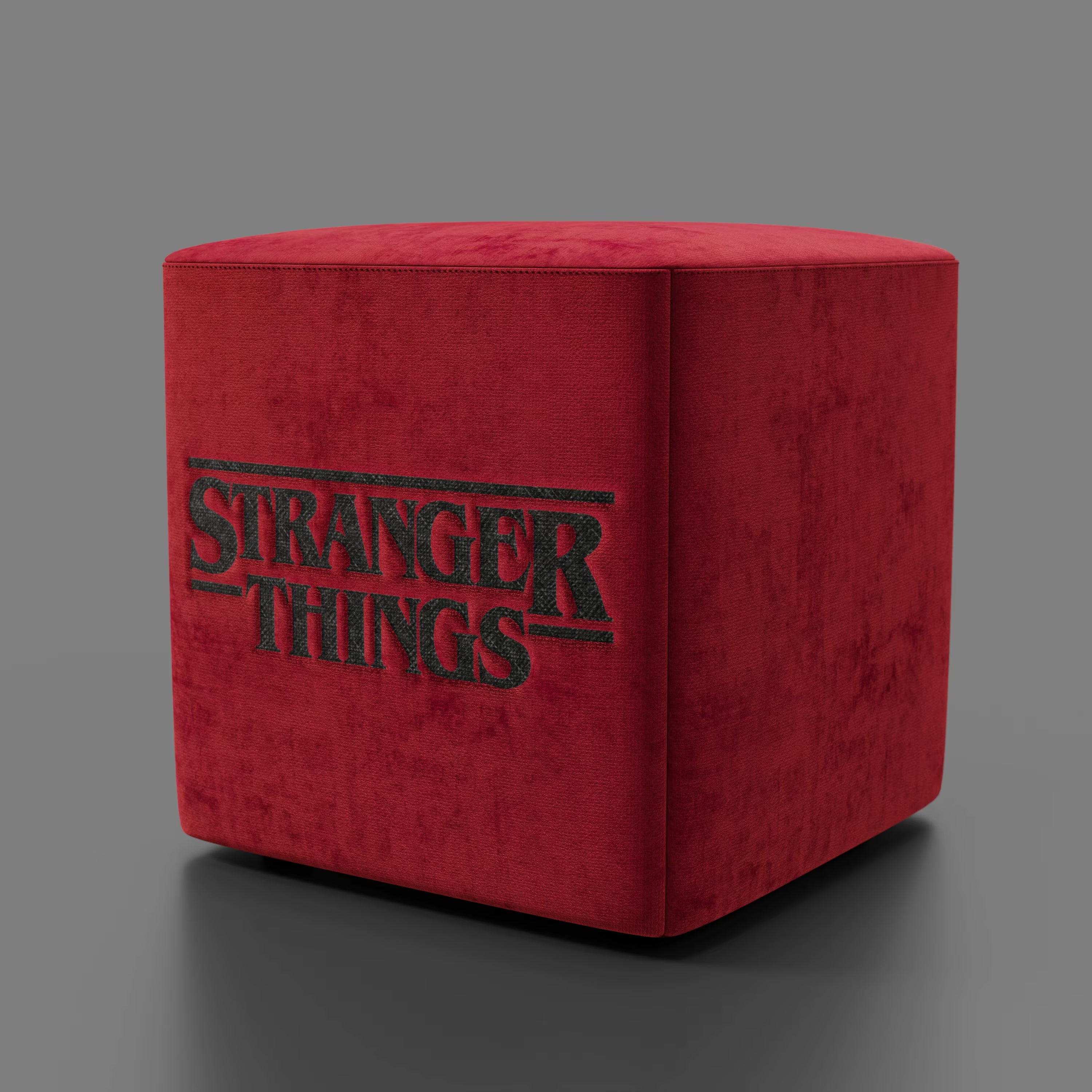 Il pouf Cube Stranger Things Edition di Divani.Store è caratterizzato da un tessuto rosso antimacchia con il logo della serie in nero, che offre un accento di stile al soggiorno. Presentato su uno sfondo grigio semplice.
