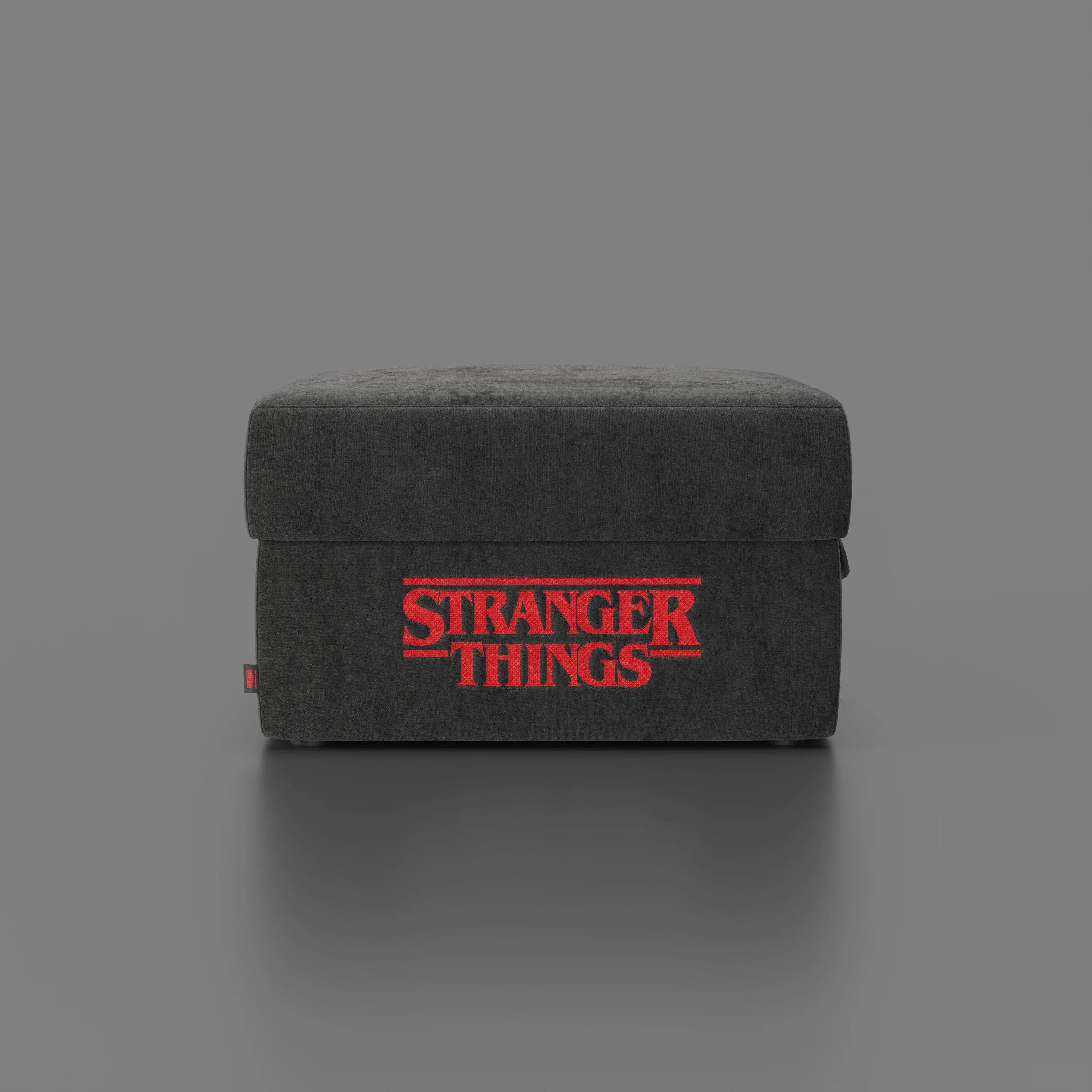 Il pouf Sun Contenitore Stranger Things Edition di Divani.Store è un pouf antracite di 60x80 cm in tessuto antimacchia, caratterizzato dal logo rosso di "Stranger Things" sul davanti e da linee moderne, su uno sfondo grigio semplice.