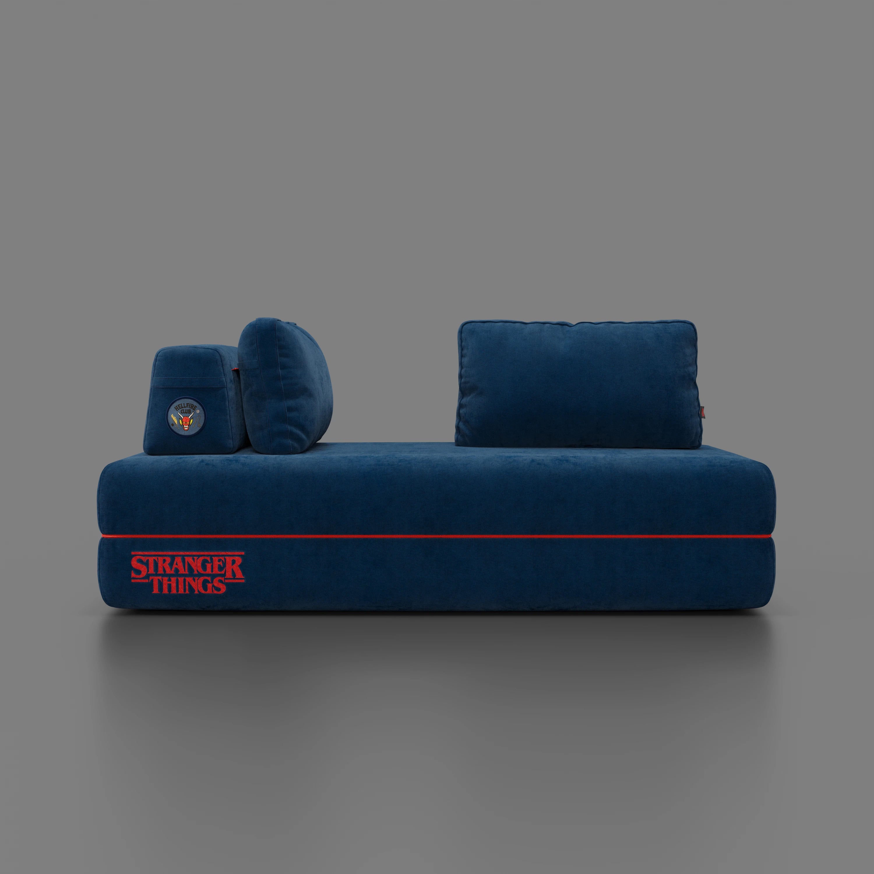 Il divano letto matrimoniale Rift STRANGER THINGS Edition di Divani.Store in tessuto blu smacchiabile è caratterizzato da schienali mobili, due o tre posti, materasso in memory foam da 22 cm e ricamo del logo rosso Show. Su uno sfondo grigio tinta unita.