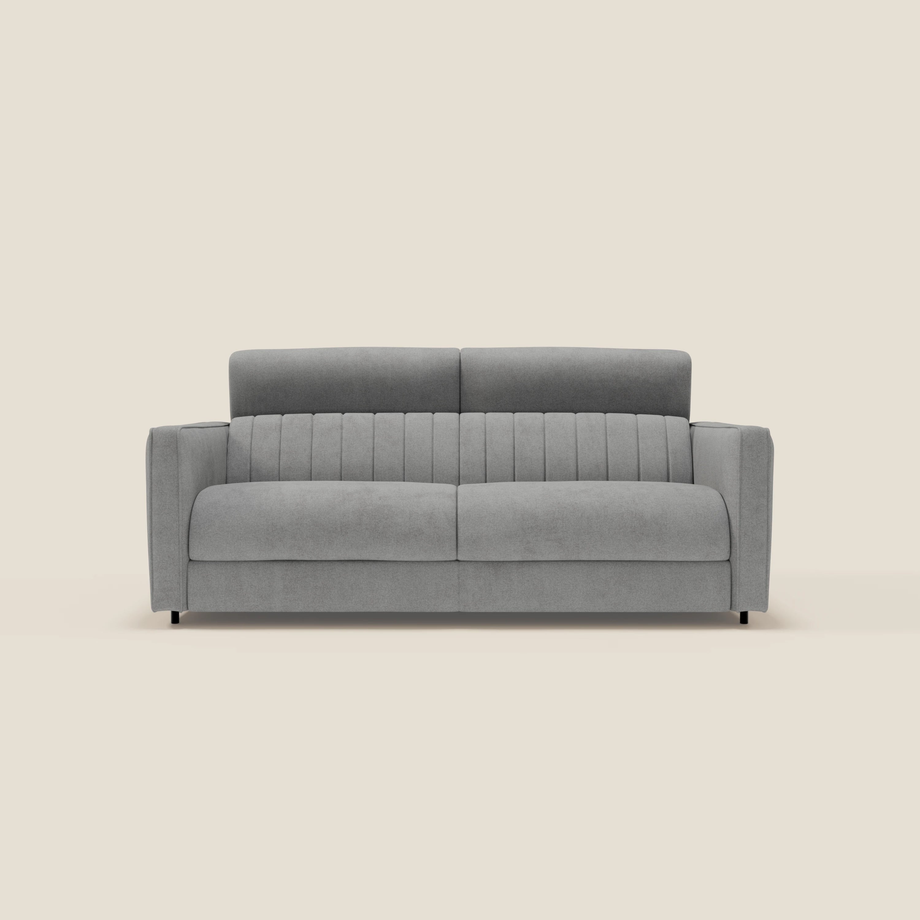 Il divano letto moderno Nivon di Divani.Store è caratterizzato da un materasso H16 cm, tessuto impermeabile grigio T25, poggiatesta regolabile, schienale a cuciture verticali, braccioli imbottiti e gambe corte nere, su uno sfondo beige chiaro.