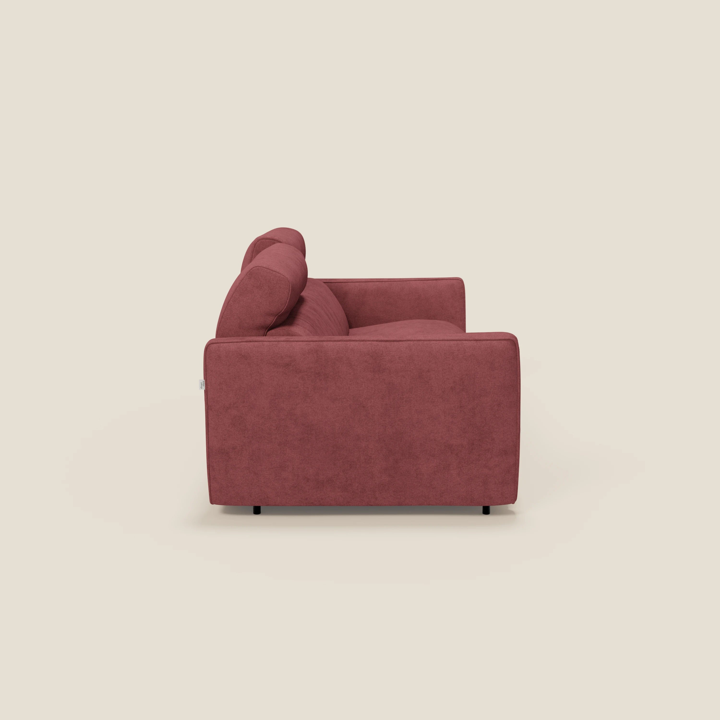 Vista laterale di Nivon Divano letto moderno di Divani.Store, rivestito in tessuto impermeabile rosso T25, con cuscini in feltro, braccioli dritti, gambe corte e scure e poggiatesta regolabile: un comfort moderno su uno sfondo beige chiaro.