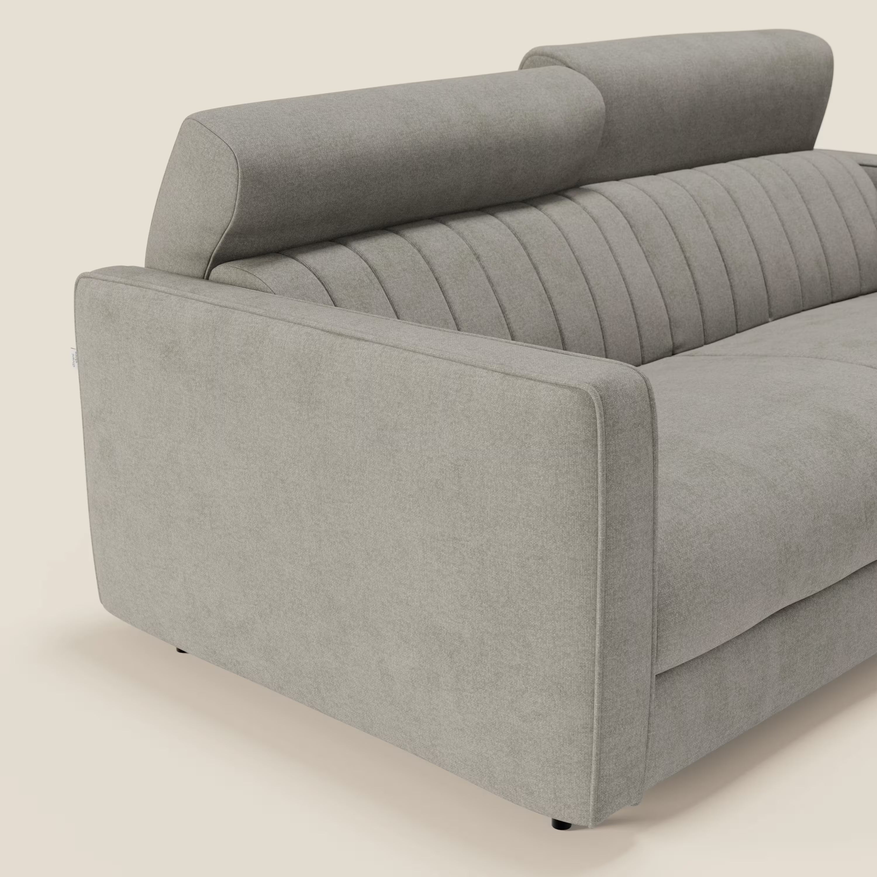 Nivon Divano letto moderno di Divani.Store è un divano letto moderno in tessuto impermeabile T25 color tortora, con materasso da 16 cm, poggiatesta regolabili, ampi braccioli, cuciture verticali a ciuffetti e design elegante, presentato ad angolo su uno sfondo bianco sporco.
