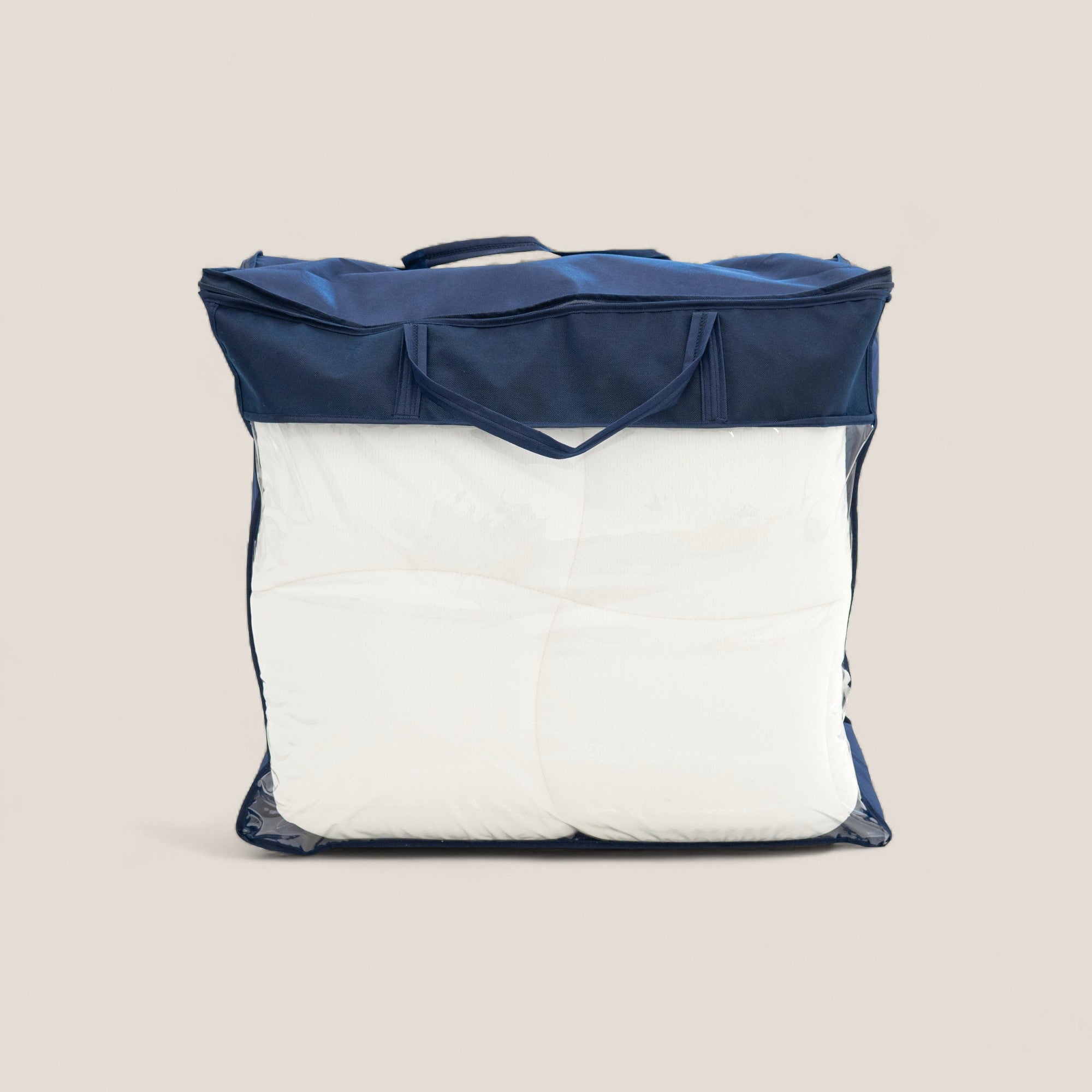 Un grande piumone bianco è contenuto in un sacchetto trasparente con finiture e manici blu, ideale per essere abbinato al Divani.Store KYROS-CLOUD Topper Luxury in Memory Foam H5 cm con Tecnologia CoolMax, su uno sfondo beige.