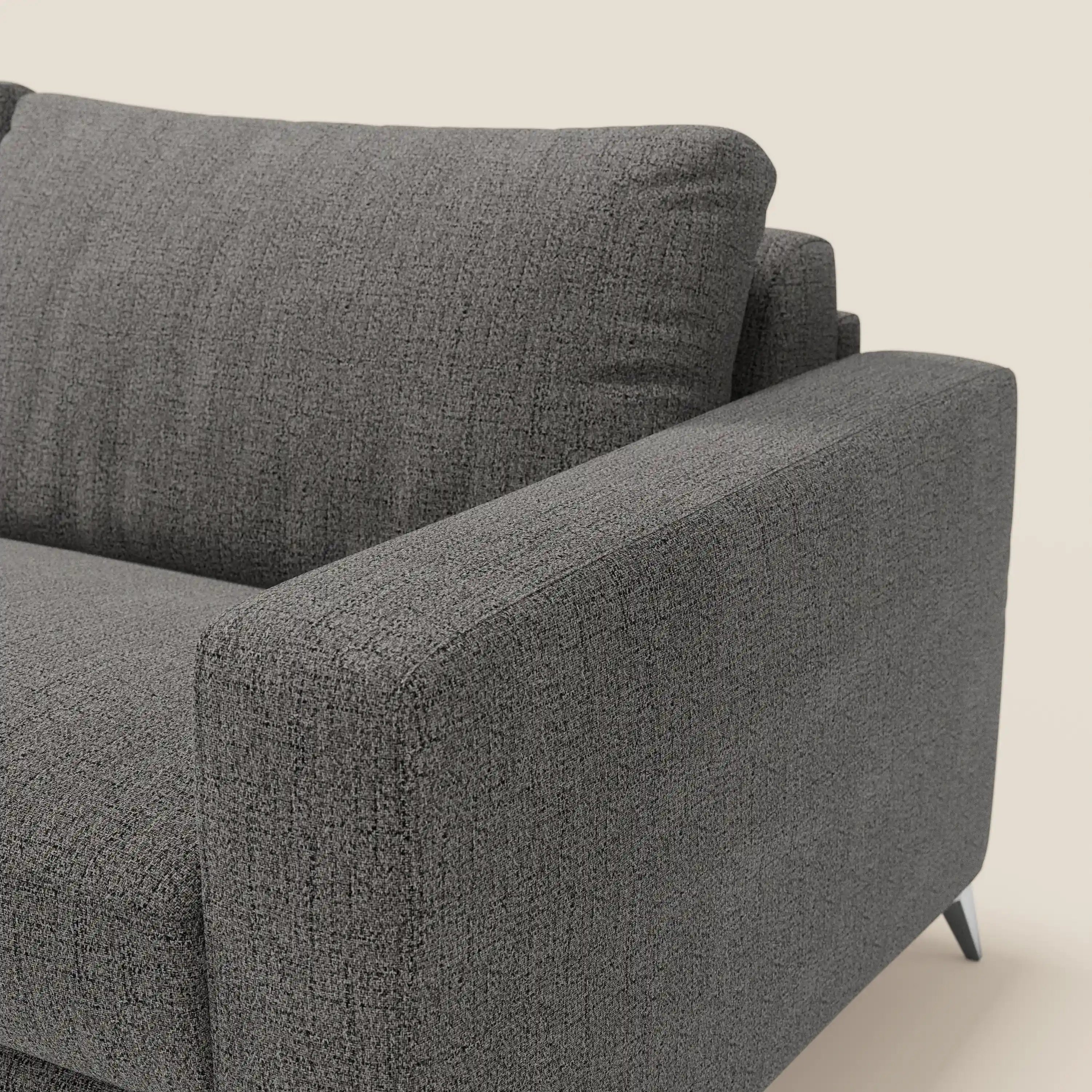 Primo piano del letto matrimoniale Alaya Divano di Divani.Store in tessuto impermeabile T03 antracite, con ampio bracciolo, cuscino dello schienale e sottili gambe angolari nere visibili su uno sfondo chiaro.