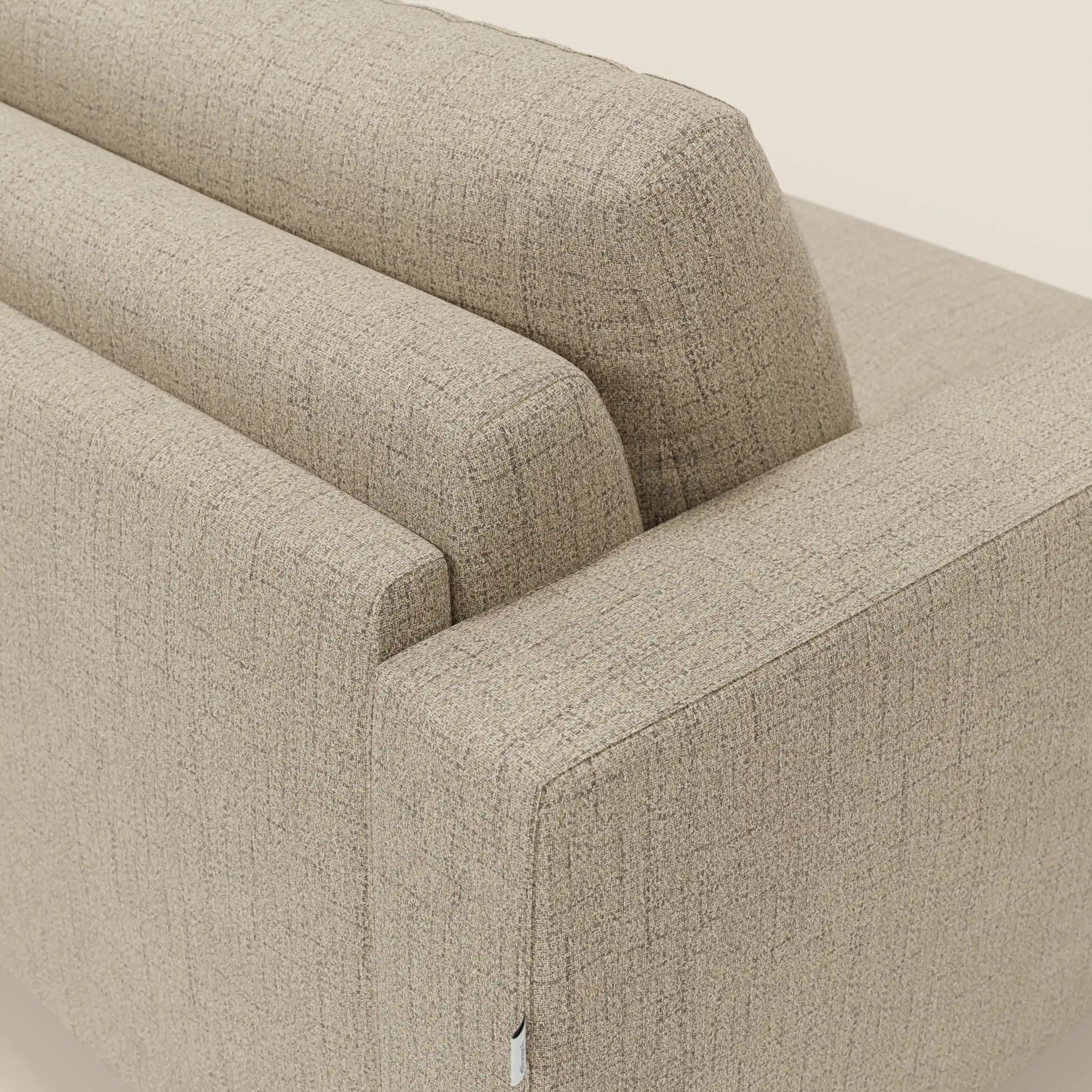 Una vista angolata e ravvicinata mostra la parte superiore dello schienale e del bracciolo di Alaya Divano letto matrimoniale di Divani.Store in tessuto impermeabile beige T03 con una texture sottile, linee pulite, design moderno e minimale e rivestimento pulito su uno sfondo semplice.