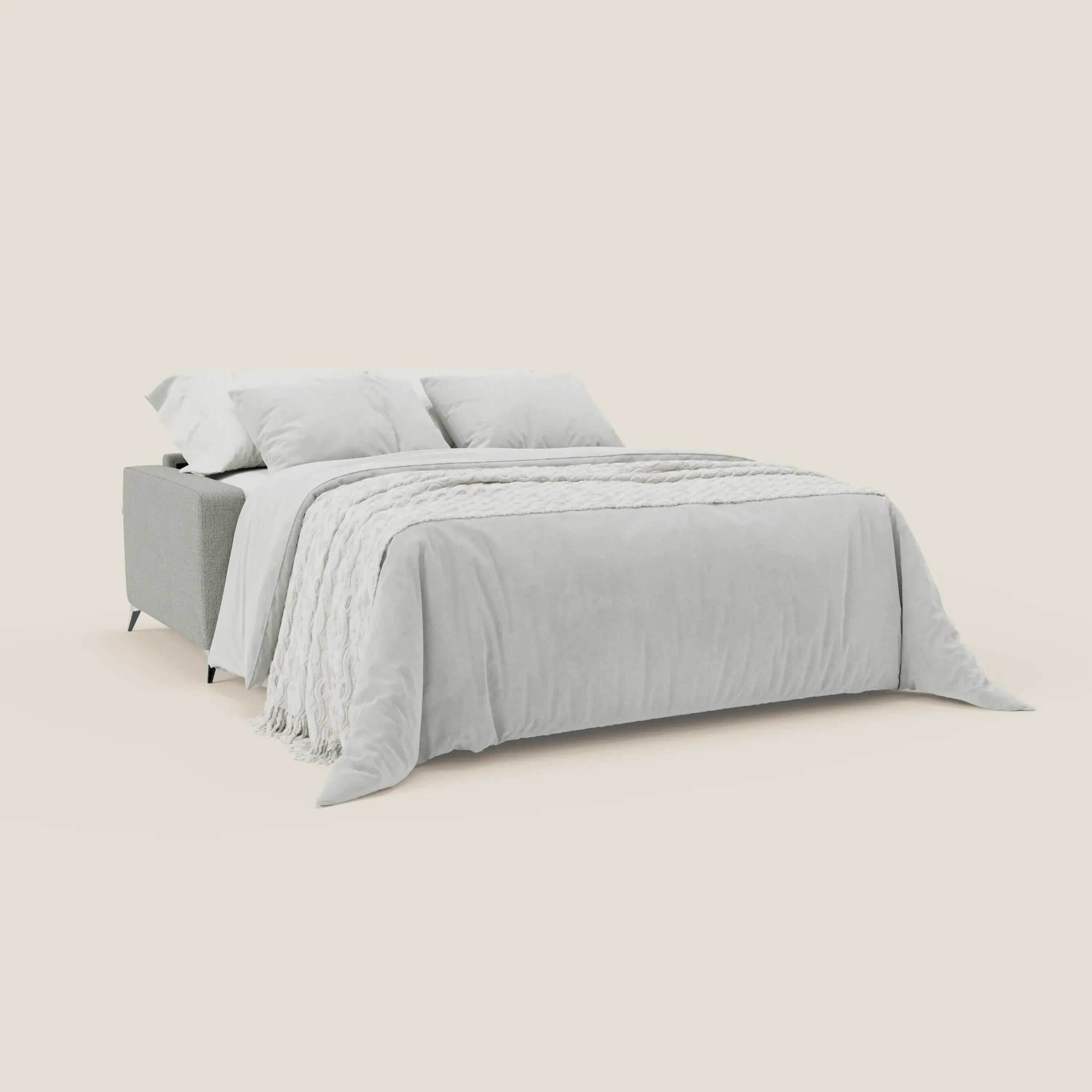 Alaya Divano letto matrimoniale di Divani.Store presenta morbidi cuscini in tessuto impermeabile T03 grigio chiaro con due cuscini bianchi, una coperta bianca piegata e un soffice piumino su sfondo beige per uno stile minimale ed elegante.
