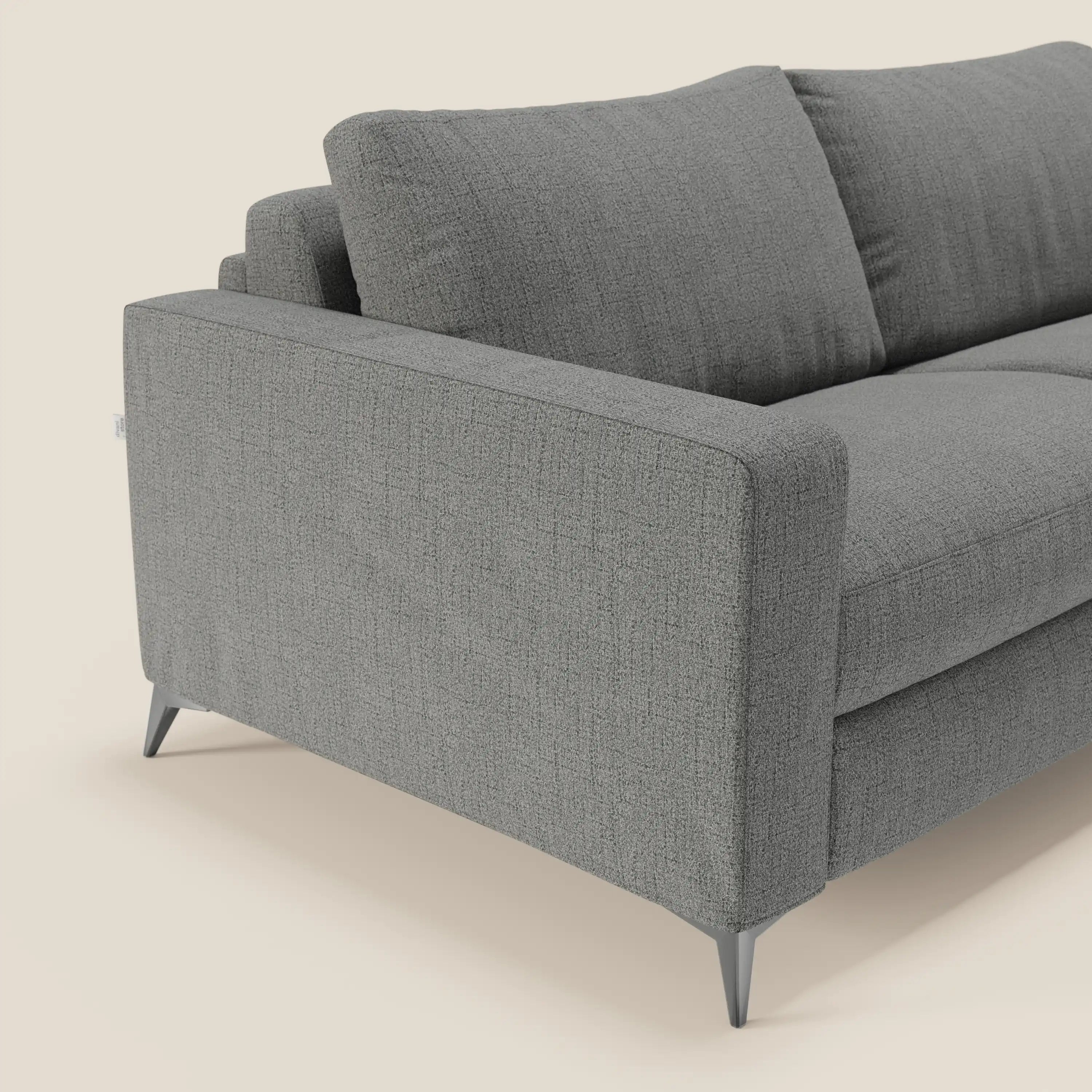 Il letto matrimoniale Alaya Divano di Divani.Store è caratterizzato da morbidi cuscini in tessuto impermeabile grigio T03, linee pulite, braccioli squadrati, due cuscini di schienale e gambe angolari in metallo. Su sfondo beige chiaro, il lato sinistro e la seduta sono parzialmente visibili.