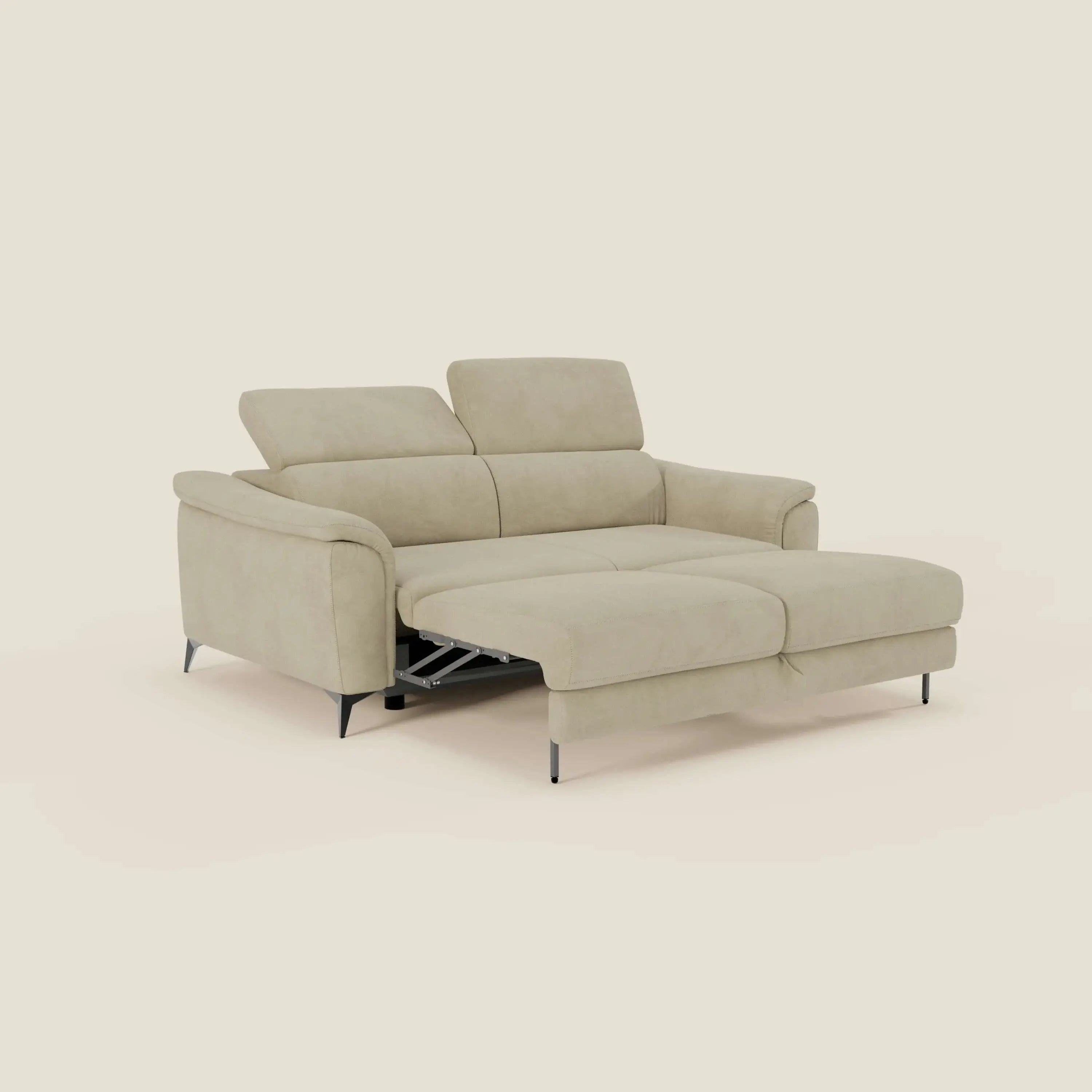 Arcos Divano 3 posti di Divani.Store in impermeabile T11 beige è dotato di poggiatesta reclinabili, alte gambe nere, bracciolo sinistro, chaise longue destra e dormeuse estraibile, parzialmente esteso su uno sfondo bianco sporco.