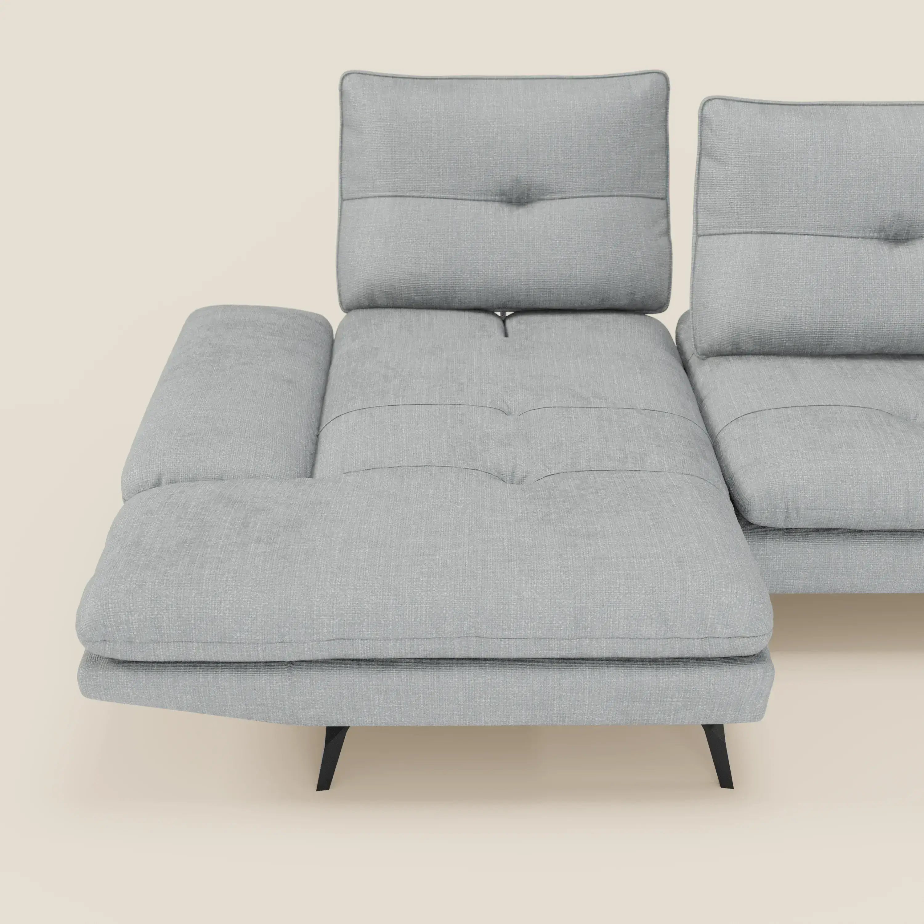 Ardex Divano con penisola di Divani.Store è caratterizzato dall'elegante tessuto impermeabile T06 ghiaccio, dai braccioli regolabili, dagli schienali scorrevoli con dettagli a bottone e dalle sottili gambe angolate nere, qui presentate su uno sfondo beige.