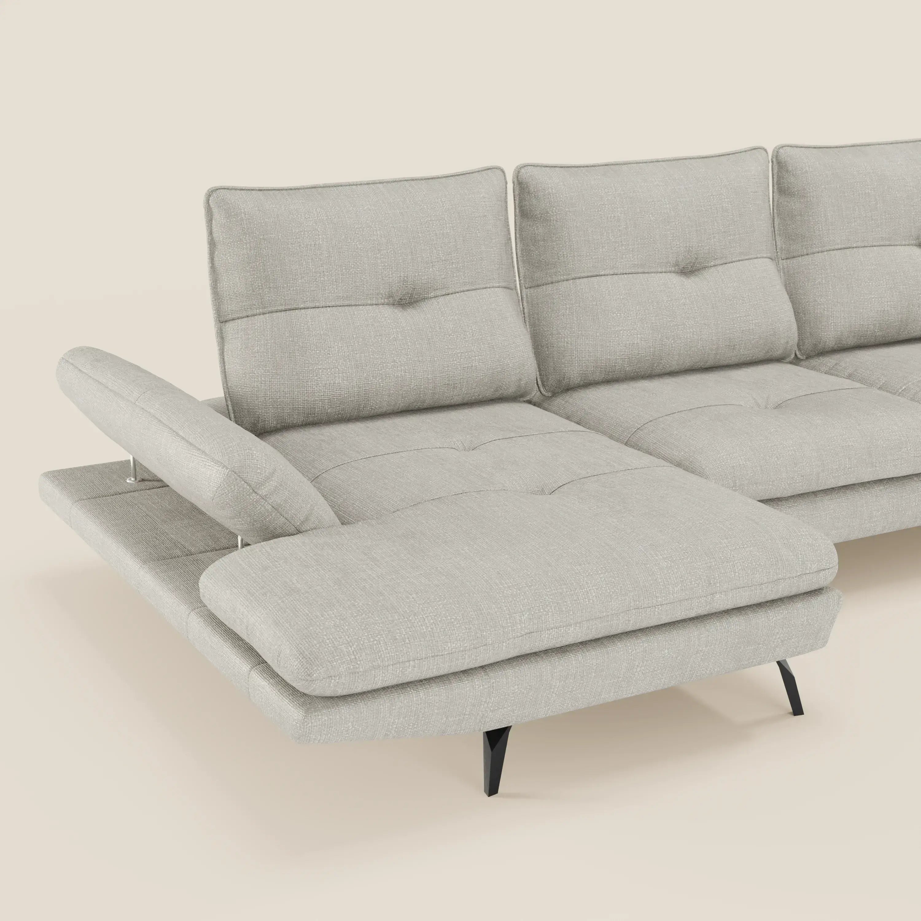 Il Divano con penisola Ardex di Divani.Store è caratterizzato da schienali traslanti, braccioli regolabili ed elegante tessuto impermeabile T06 grigio chiaro, che poggia su sottili gambe in metallo nero su un semplice sfondo bianco sporco.