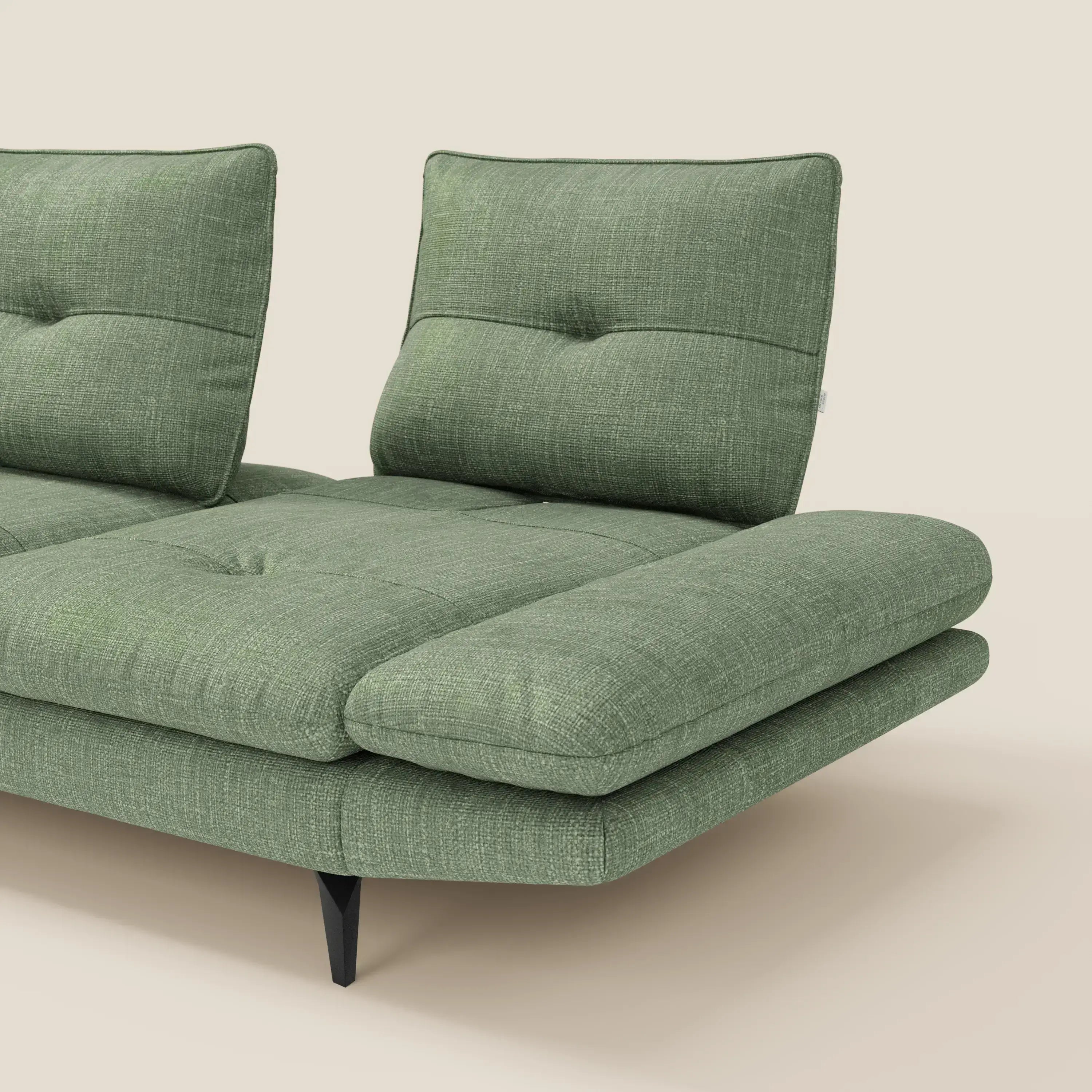 L'Ardex Divano con penisola di Divani.Store è caratterizzato da un elegante tessuto impermeabile verde T06, da ampi cuscini trapuntati, da due schienali verticali traslanti, da braccioli regolabili e da eleganti gambe angolari nere, su uno sfondo beige chiaro.