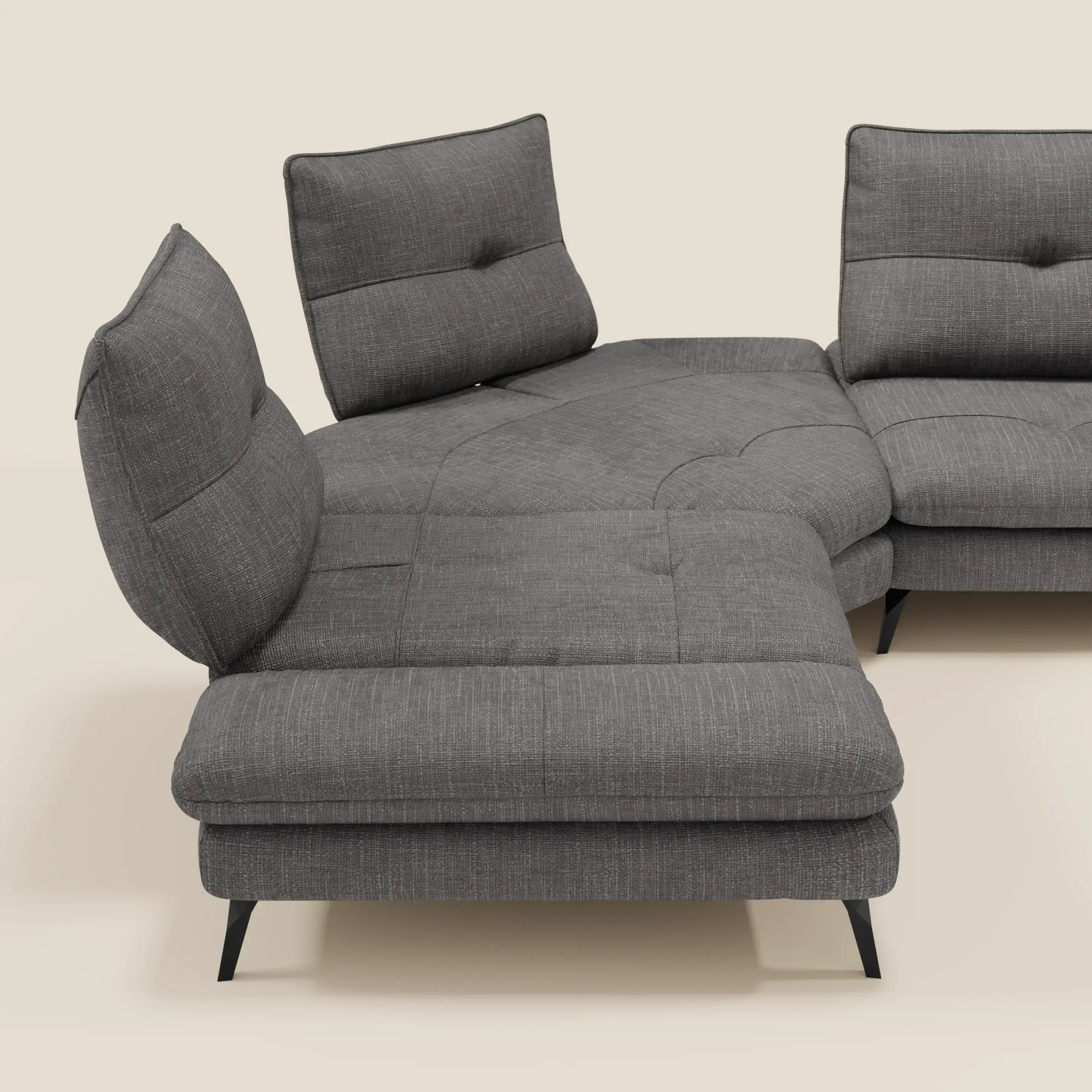 Il Divano Angolare Ardex di Divani.Store è caratterizzato da schienali traslanti, bracciolo regolabile ed elegante tessuto impermeabile T06 antracite. È dotato di cuscini trapuntati e di gambe angolari in metallo nero, su uno sfondo beige chiaro.