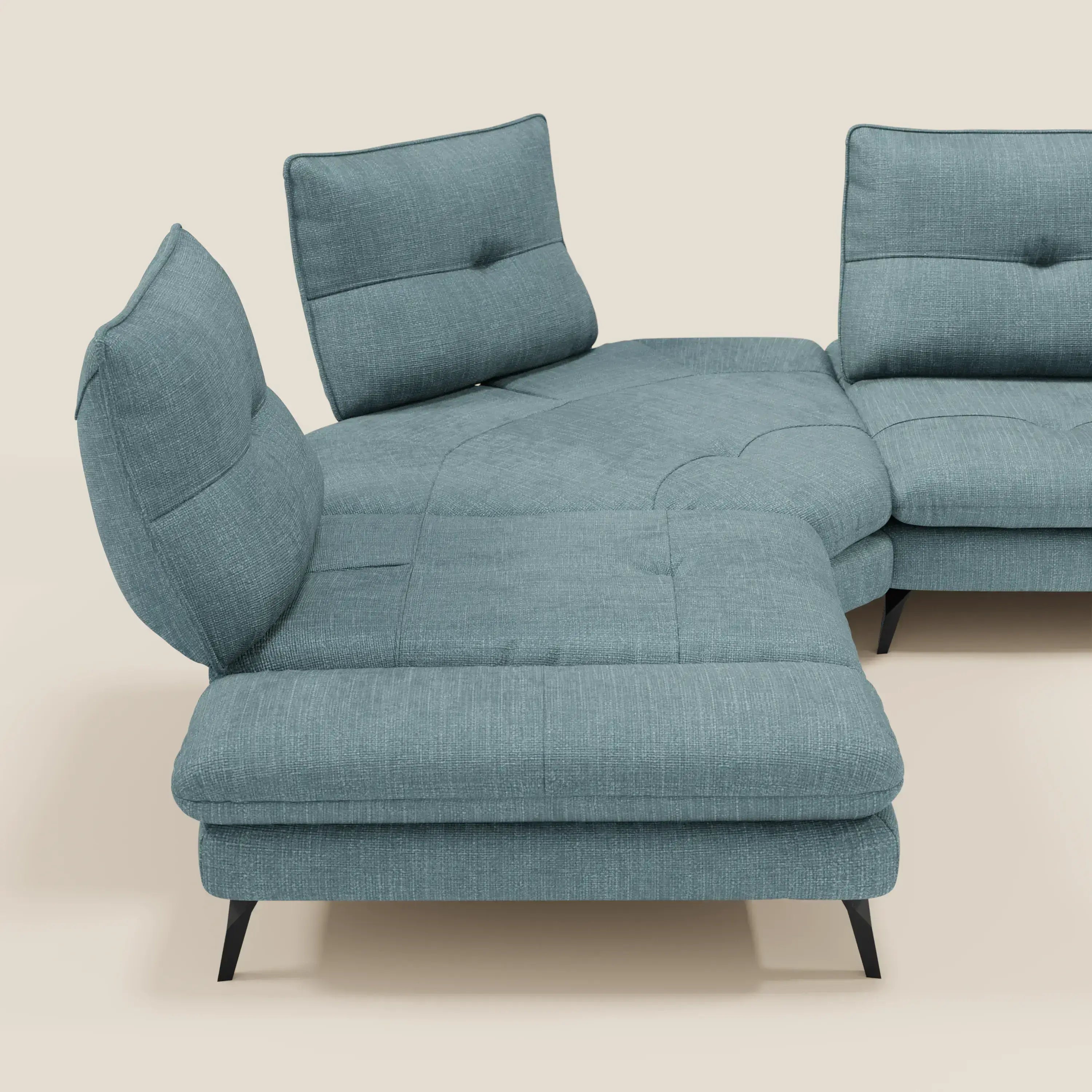 Ardex Divano Angolare di Divani.Store è caratterizzato da schienali traslanti, bracciolo regolabile e cuscini trapuntati in elegante tessuto impermeabile T06 azzurro con gambe angolari nere, su sfondo beige chiaro.