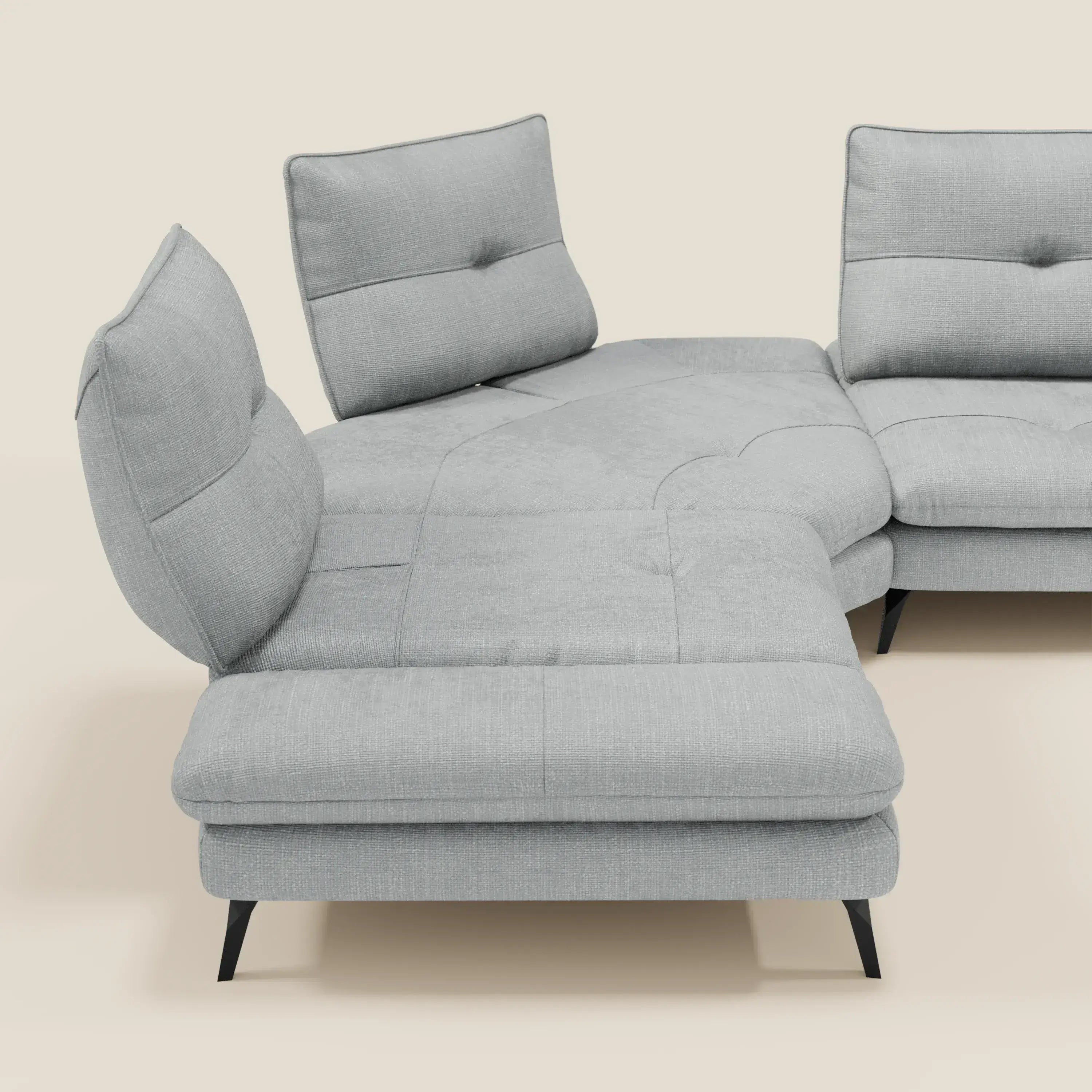 Ardex Divano Angolare di Divani.Store, in elegante tessuto impermeabile T06 ghiaccio, è dotato di schienale scorrevole e bracciolo regolabile. Le sue linee pulite e il suo design modulare sono evidenziati su uno sfondo beige con gambe angolari nere.