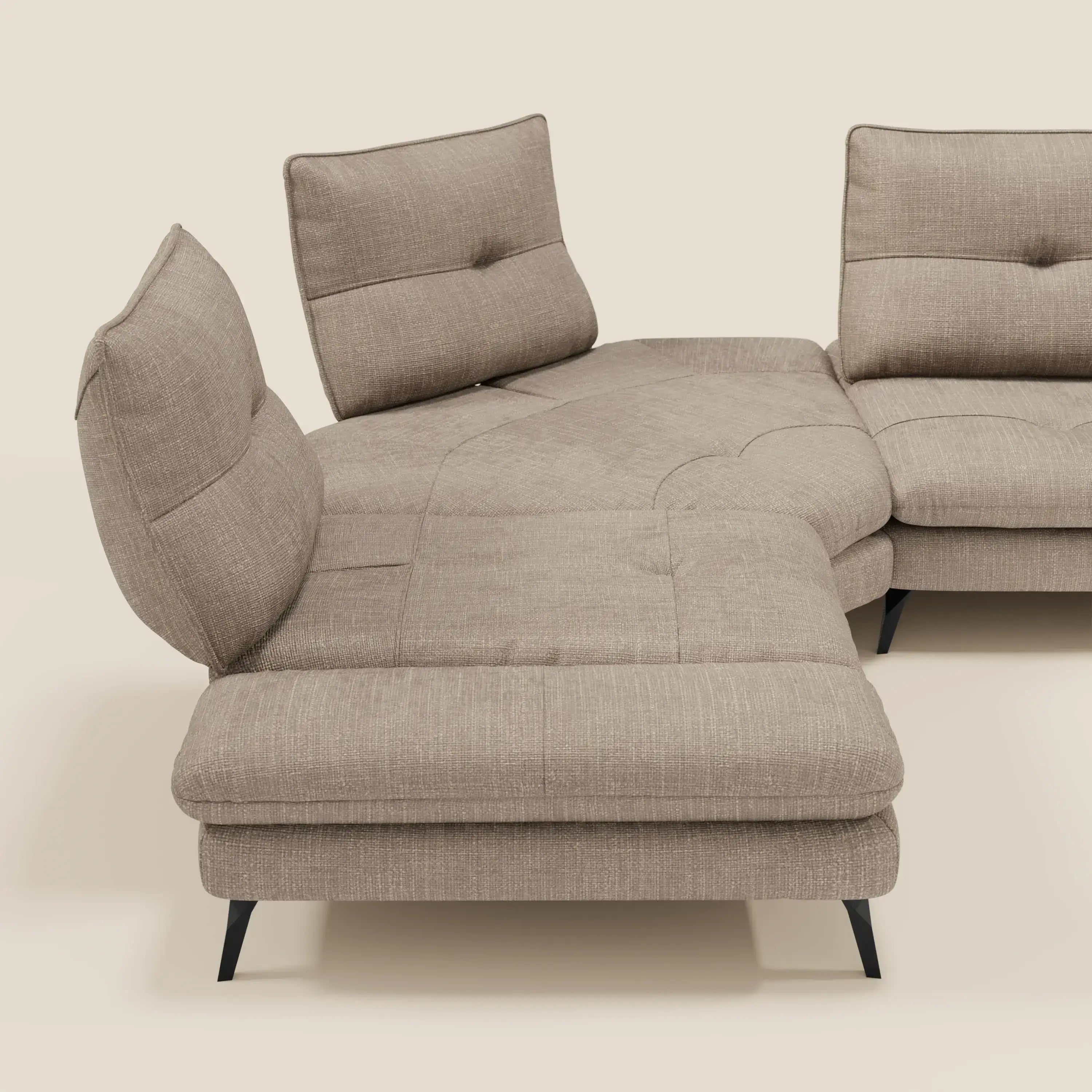 Ardex Divano Angolare di Divani.Store è dotato di tre schienali regolabili e di un bracciolo mobile in elegante tessuto tortora T06, resistente all'acqua. Le gambe angolari nere contrastano elegantemente con il fondo beige chiaro.