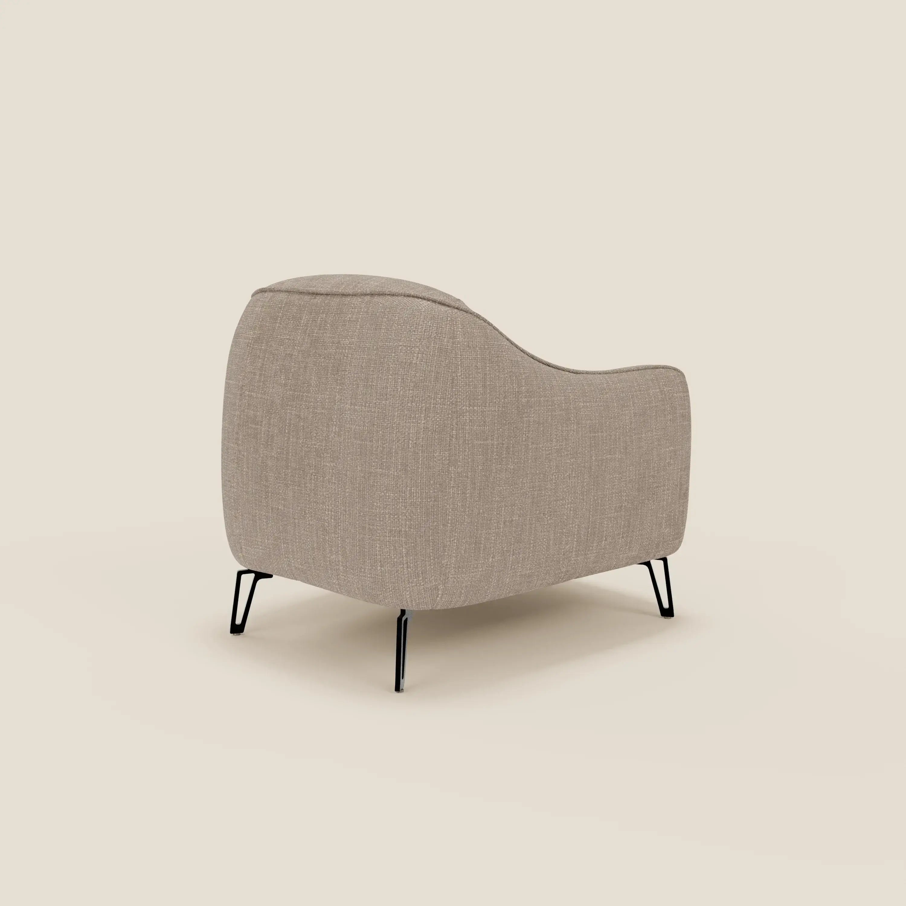 Avela Poltroncina di Divani.Store è caratterizzata da un comfort senza tempo in morbido tessuto tortora T06 impermeabile, con schienale curvo e sottili gambe in metallo nero. Presentata su uno sfondo crema, il suo design minimalista e moderno è inclinato per mostrare la schiena e il fianco.