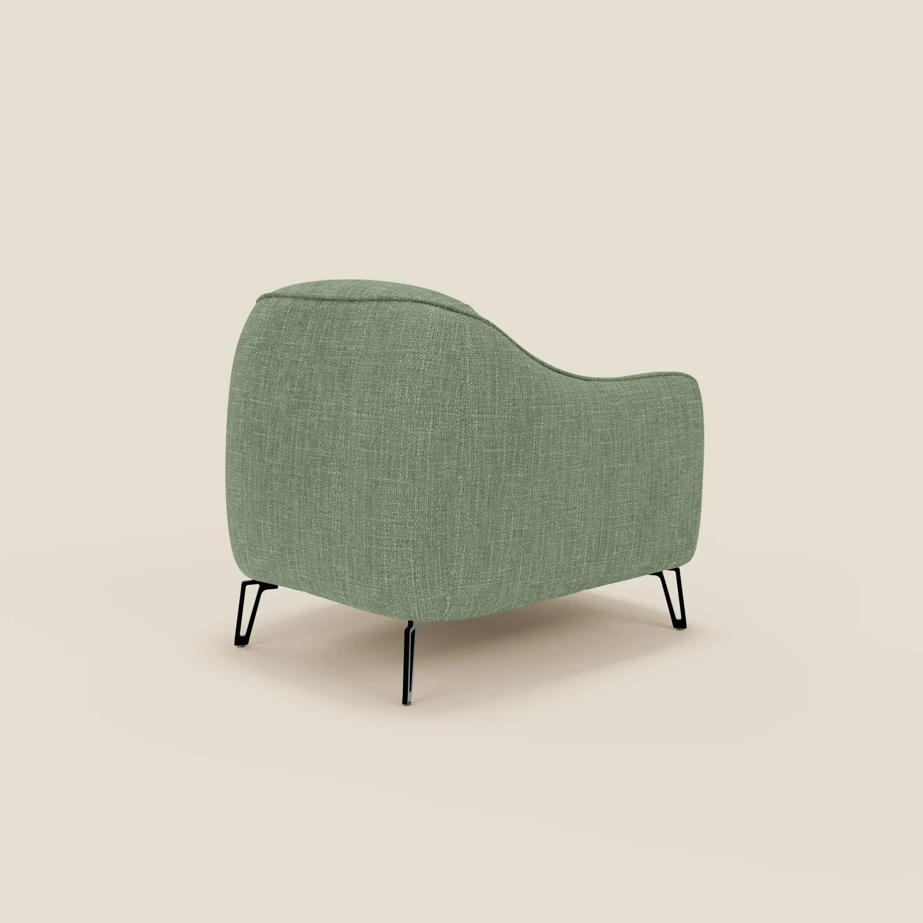 Avela Poltroncina di Divani.Store vanta un comfort senza tempo grazie al tessuto liscio impermeabile verde T06, alle sottili gambe in metallo nero e allo schienale moderno e arrotondato, che presenta uno stile minimalista su uno sfondo beige.