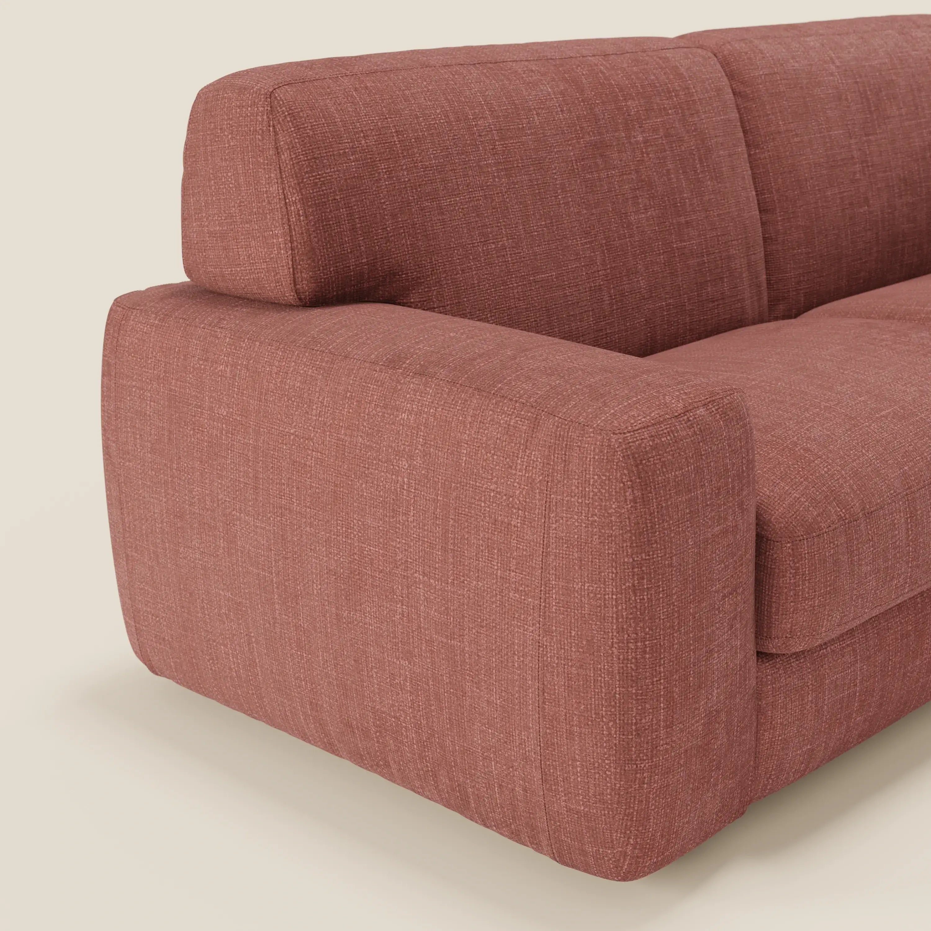 Un primo piano del letto materasso Cloud Divano H17 cm di Divani.Store in corallo impermeabile T06 mostra il suo design moderno, i morbidi cuscini, l'ampio bracciolo e lo schienale imbottiti, il tutto su uno sfondo chiaro.