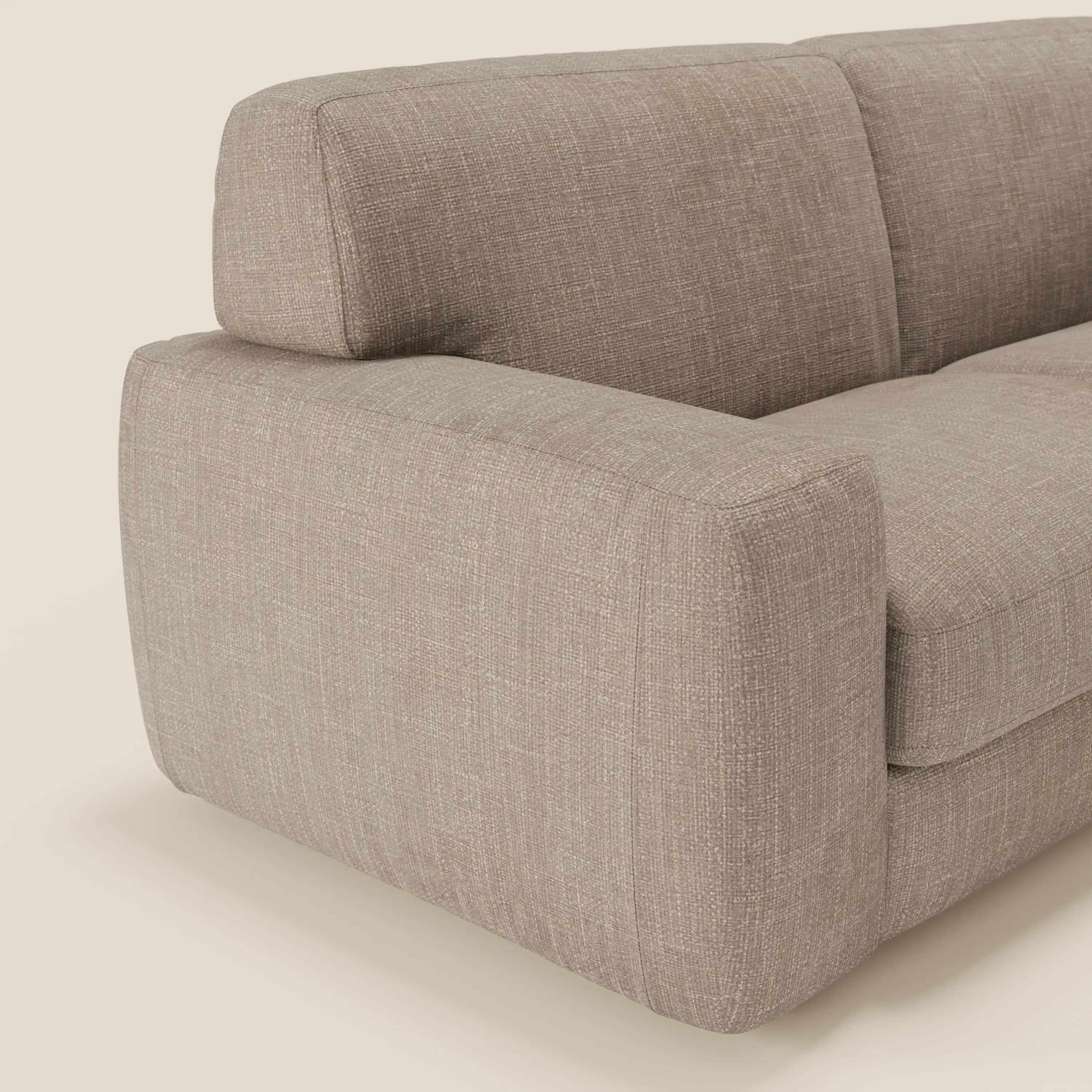 Un primo piano del divano letto materasso Cloud H17 cm di Divani.Store, caratterizzato da spessi braccioli e morbidi cuscini in tessuto impermeabile T06 tortora, mette in mostra il comfort quotidiano e il design compatto su uno sfondo chiaro.