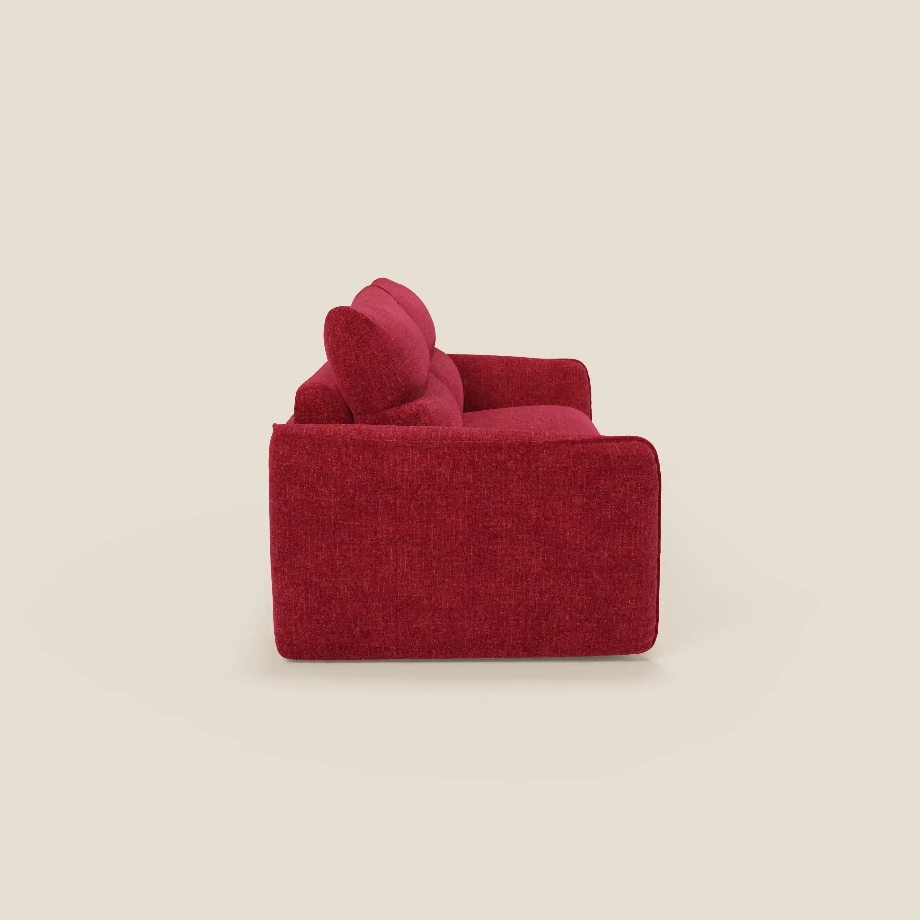 Il divano letto Elios di Divani.Store, presentato di lato con un bracciolo, è caratterizzato da cuscini morbidi spalliera e tessuto smacchiabile T24 rosso bordeaux per una facile pulizia. Gli spessi cuscini e il design squadrato spiccano sullo sfondo beige.