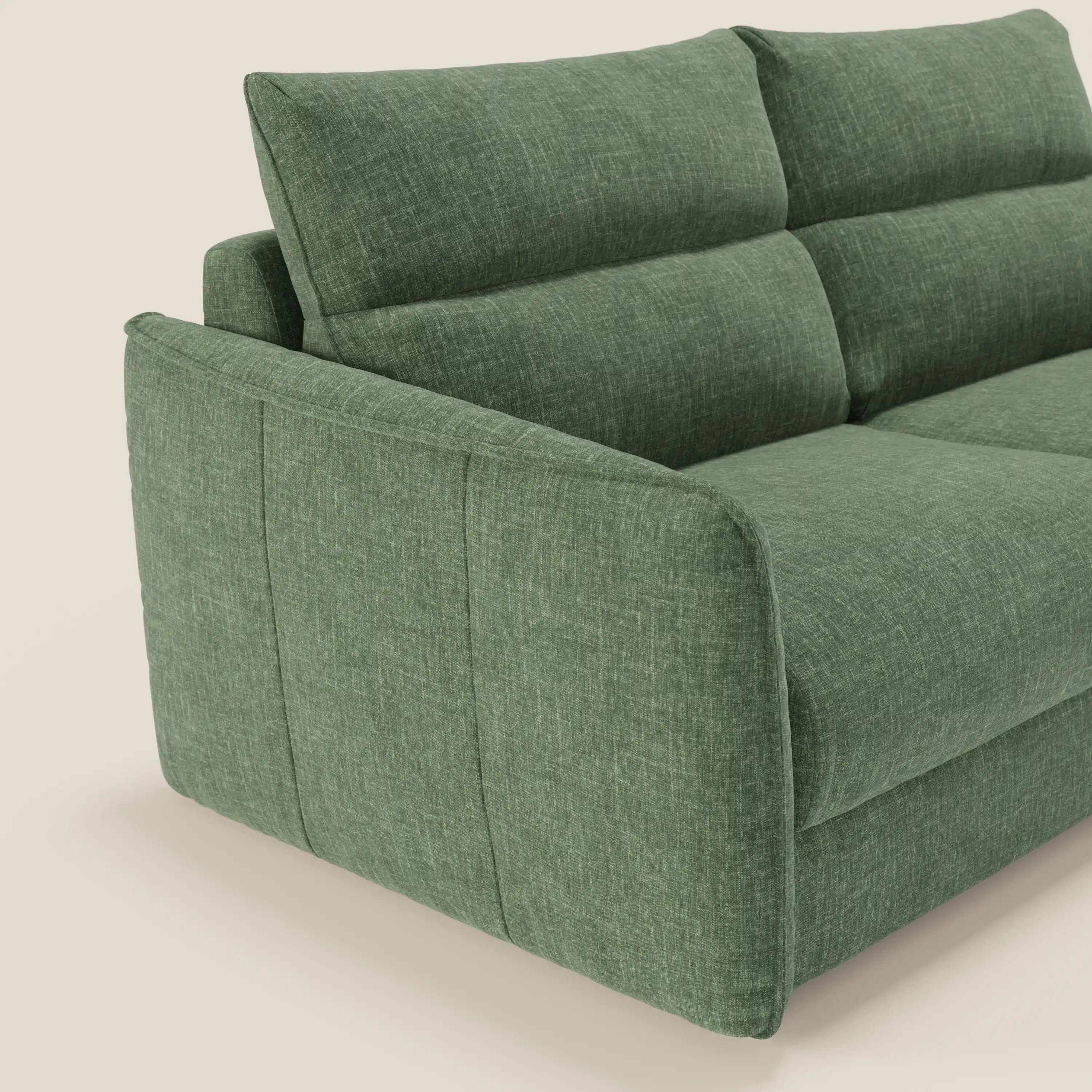 Il Divano letto Elios di Divani.Store in tessuto smacchiabile T24 verde oliva è presentato lateralmente, con ampi braccioli, cuscini di schienale e un design moderno. Il suo colore e la sua struttura spiccano su un semplice sfondo bianco sporco.