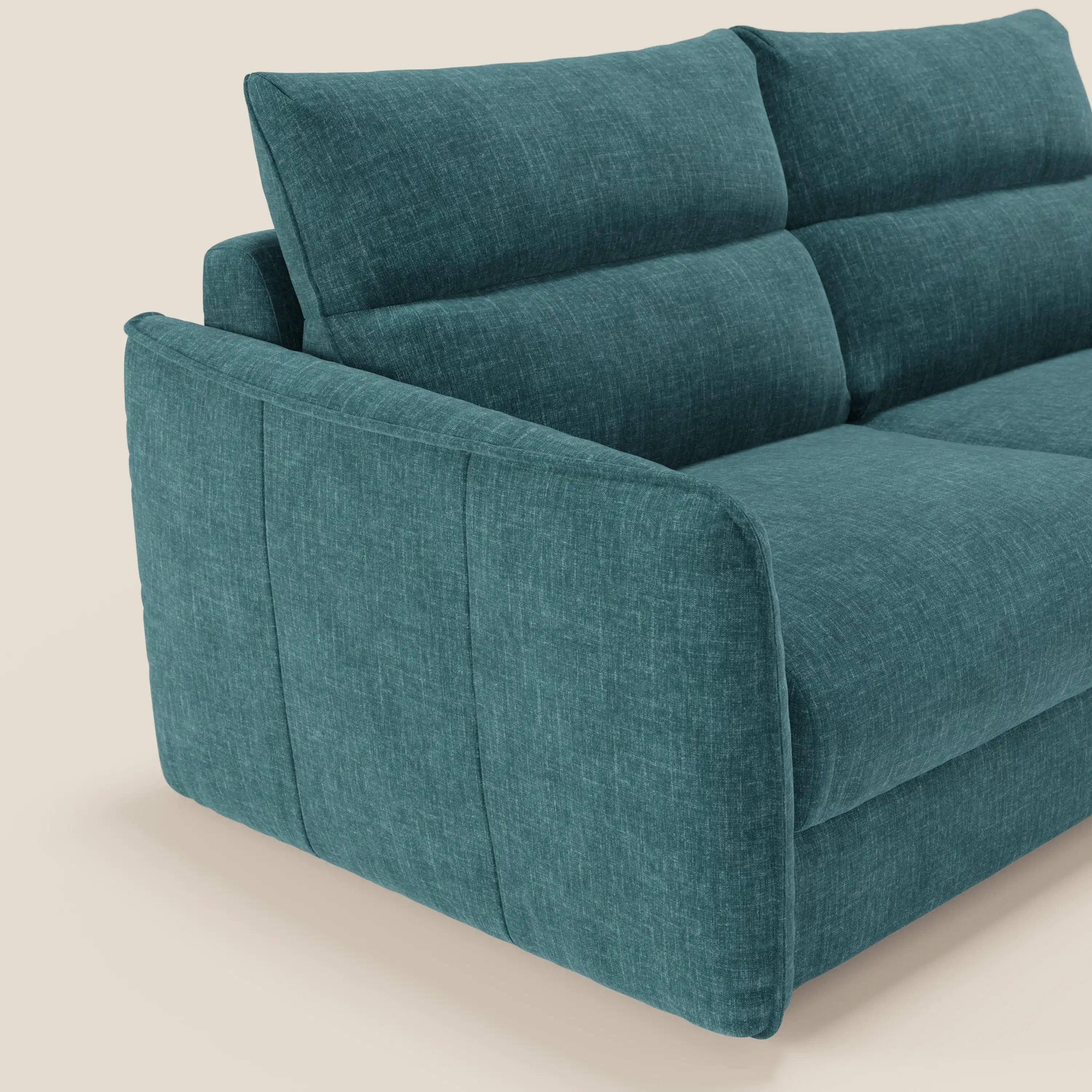 Primo piano del Divano letto Elios di Divani.Store, caratterizzato da spalliera di cuscini morbidi e tessuto smacchiabile T24 petrolio, con bracciolo e schienale spessi e confortevoli, su uno sfondo beige chiaro.