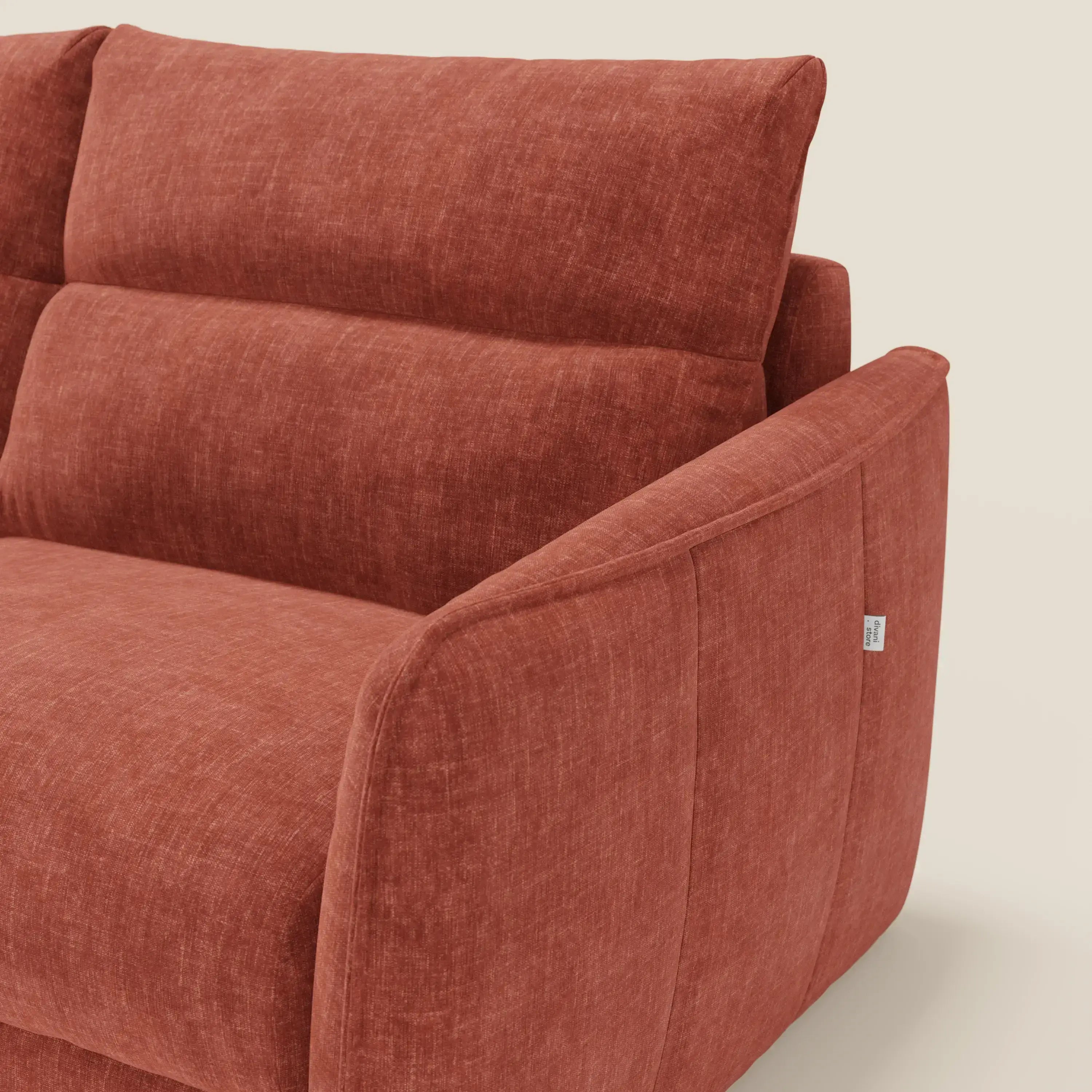 Primo piano di Elios Divano letto di Divani.Store, caratterizzato da morbidi cuscini di schienale in tessuto ruggine T24 antimacchia, schienale angolato, seduta profonda, ampio bracciolo e targhetta laterale in tessuto su sfondo bianco sporco.