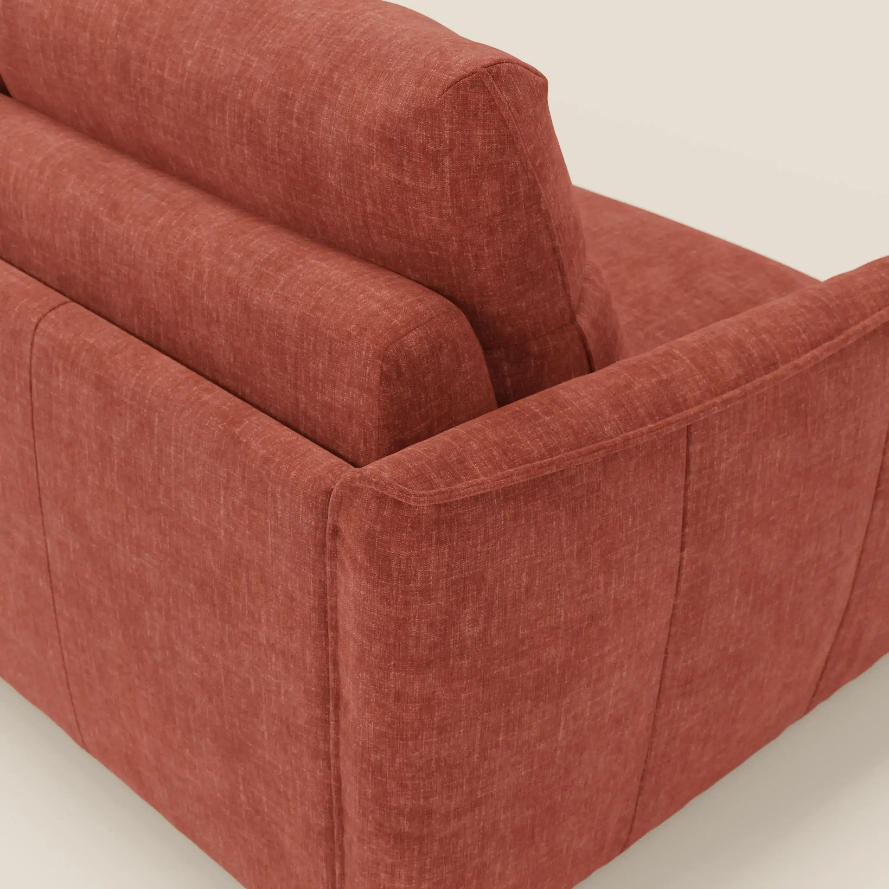 Una vista dettagliata del tappeto Elios Divano letto con morbidi cuscini spalliera in tessuto smacchiabile T24 di Divani.Store mette in evidenza il suo tessuto strutturato color ruggine, i cuscini dello schienale, le cuciture a vista e le linee moderne su uno sfondo neutro.