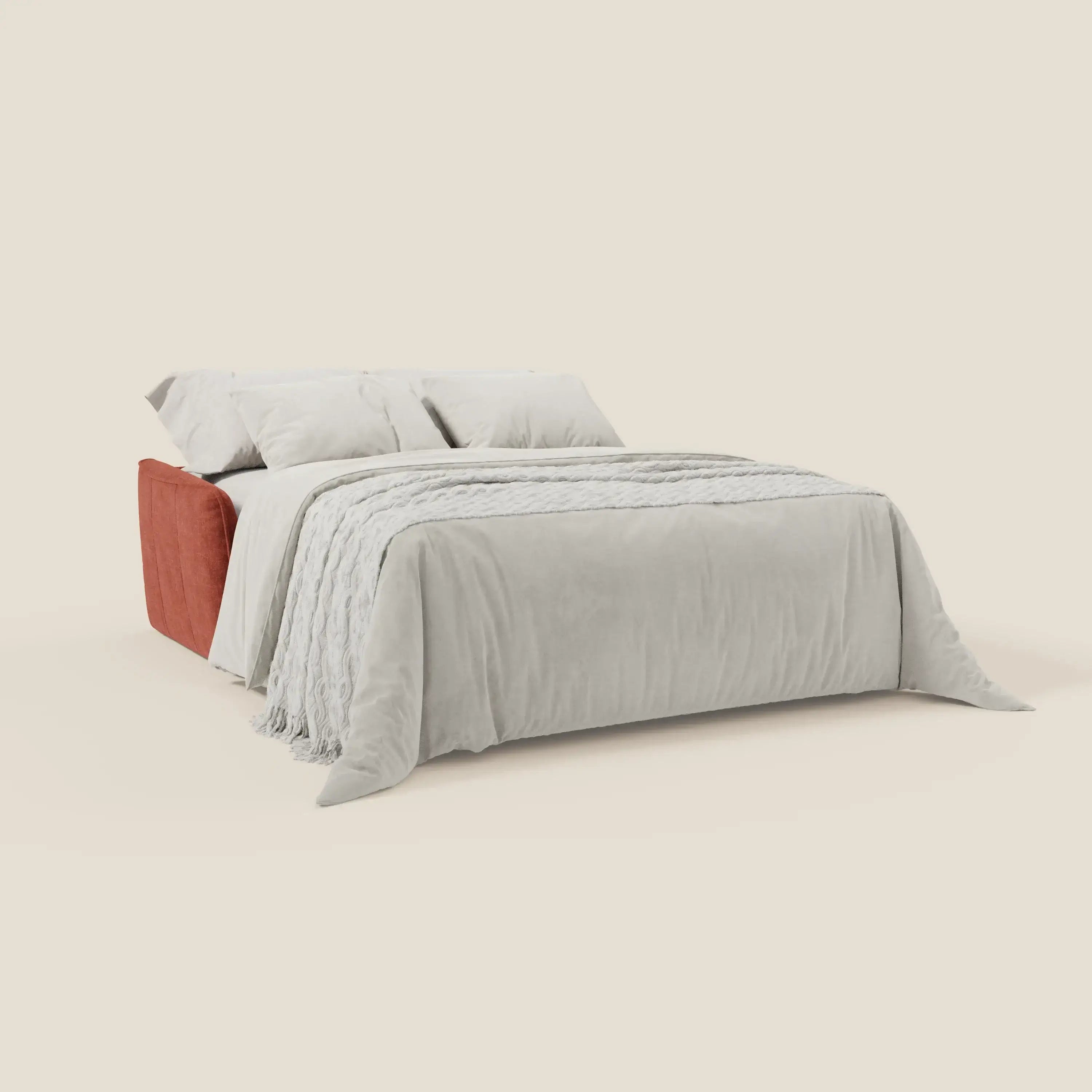 Il letto Elios Divano di Divani.Store, caratterizzato da morbidi cuscini in tessuto antimacchia T24 color ruggine, è abbinato a lenzuola e cuscini grigio chiaro su uno sfondo beige senza cuciture, con una coperta strutturata drappeggiata ai piedi del letto.