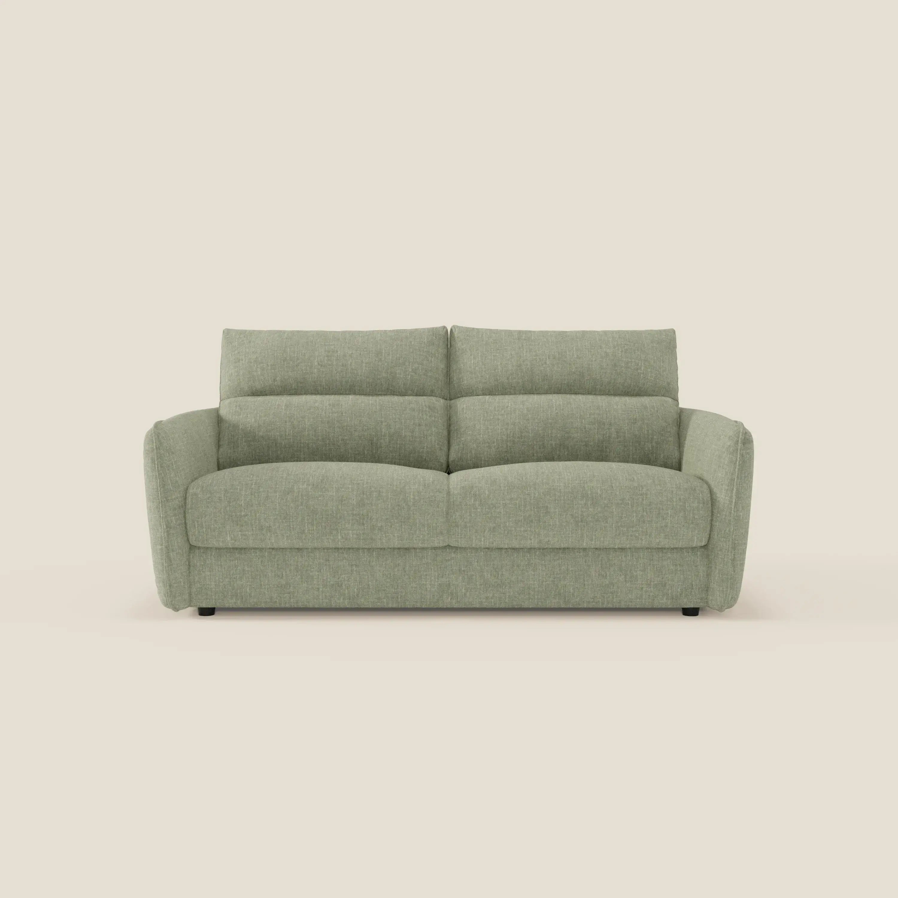 Elios Divano letto di Divani.Store è caratterizzato da morbidi cuscini di schienale in tessuto T24 verde salvia, antimacchia, due cuscini di seduta e di schienale, ampi braccioli, gambe corte nere e un look moderno su uno sfondo beige chiaro.