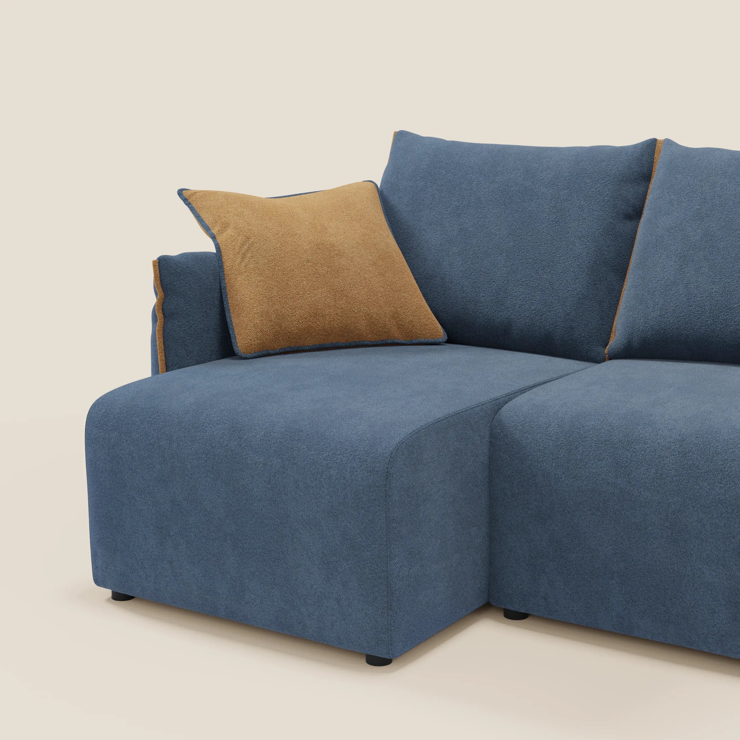 Il Divano angolare reversibile Flexar di Divani.Store è caratterizzato da un'imbottitura in bouclé impermeabile blu, sedili allungabili, gambe basse nere e cuscino d'accento arancione. Il tutto su uno sfondo bianco chiaro.