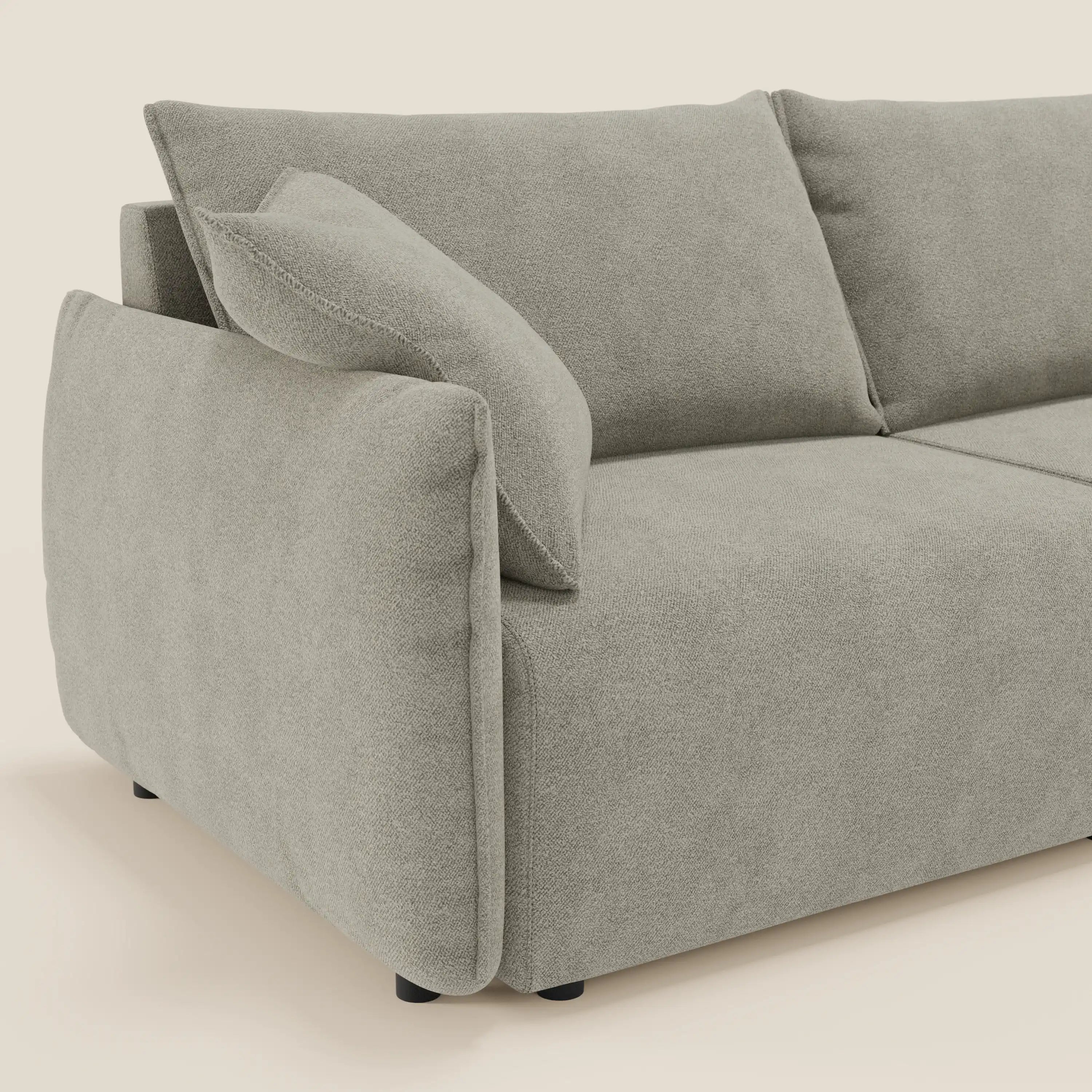 Un primo piano del divano Flexar con sedute allungabili e schienale in piuma di Divani.Store mette in evidenza gli spessi cuscini in morbido bouclé impermeabile T07 beige, i braccioli profondi, il cuscino angolato e le corte gambe nere su uno sfondo neutro.