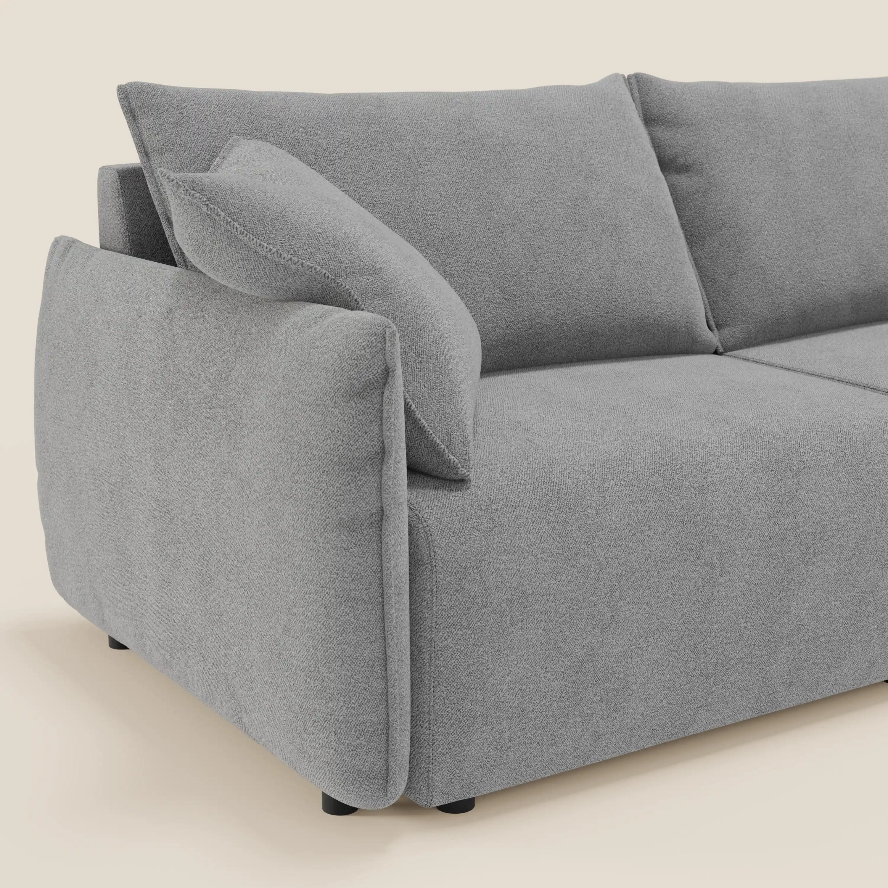 Primo piano del divano Flexar con sedute allungabili e schienale in piuma di Divani.Store in morbido bouclé impermeabile T07 grigio, caratterizzato da cuscini in peluche e cuscino coordinato, bordi arrotondati e gambe corte nere su uno sfondo neutro.