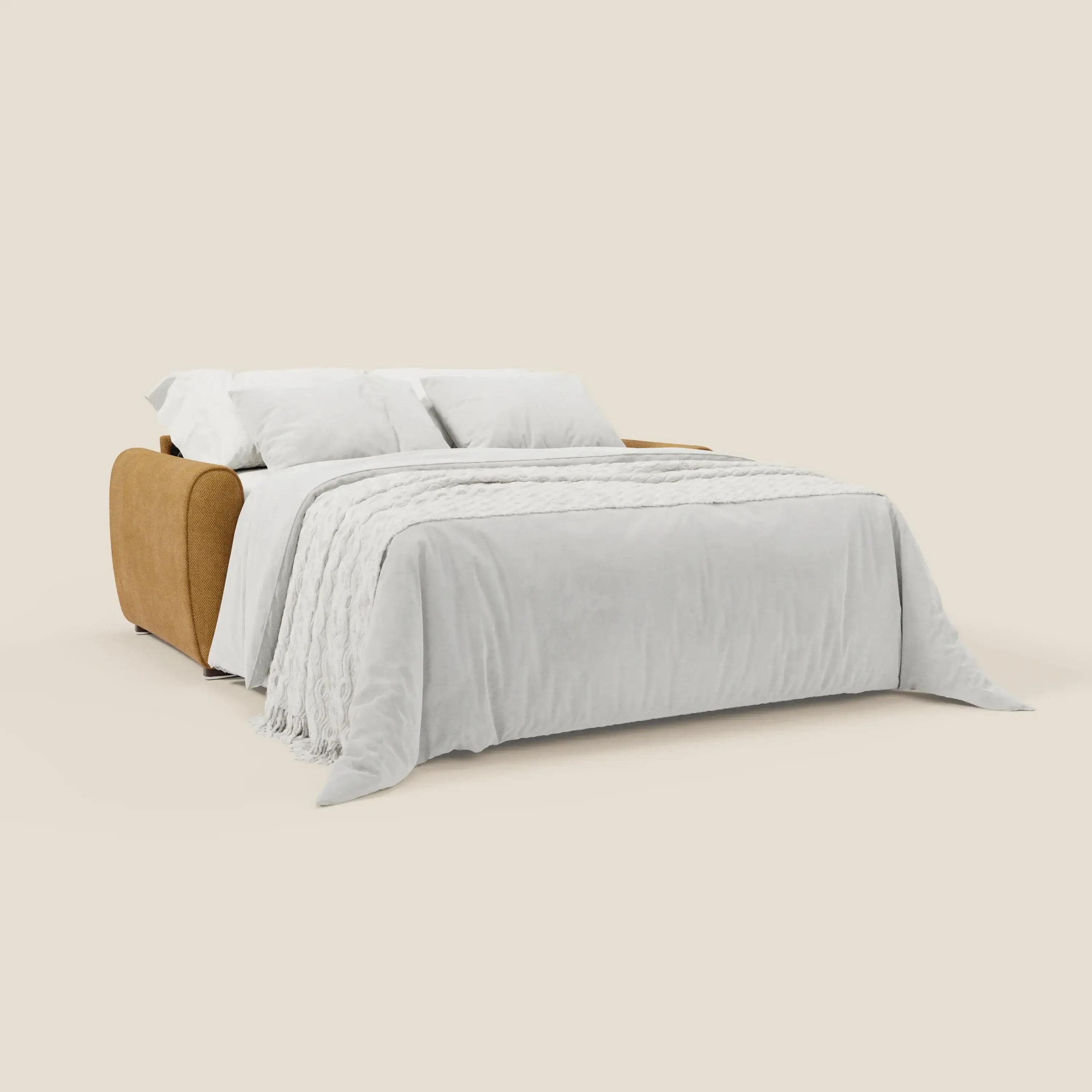 Il Kaleo Divano letto moderno di Divani.Store, rivestito in tessuto impermeabile T26 giallo e dotato di materasso H17 cm, è aperto a letto con morbida coperta bianca e due grandi cuscini bianchi su sfondo beige chiaro.