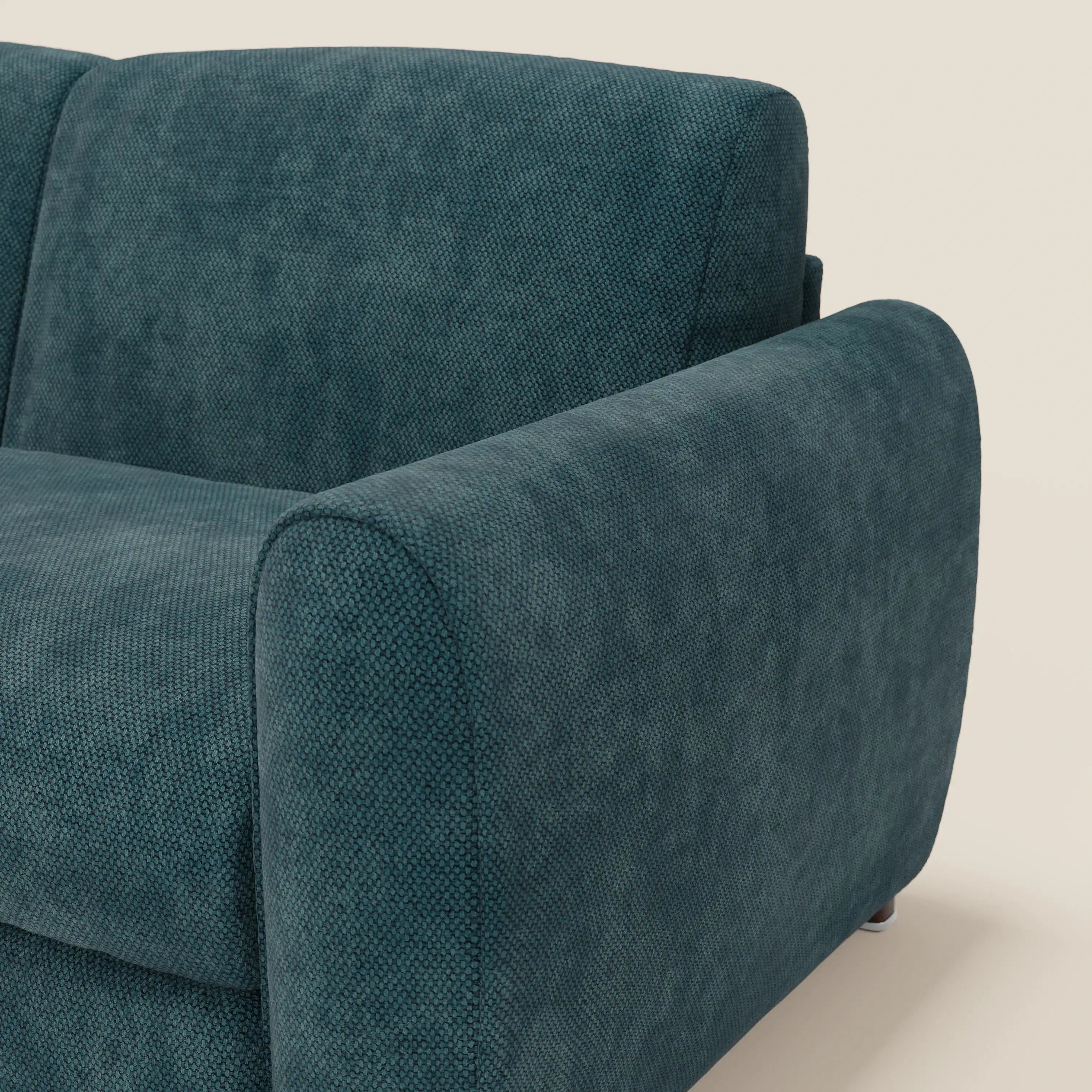 Un primo piano del Kaleo Divano letto moderno con materasso H17 cm di Divani.Store, in raffinato tessuto impermeabile T26 petrolio, mette in evidenza il bracciolo arrotondato, la seduta morbida e le linee eleganti su uno sfondo semplice.
