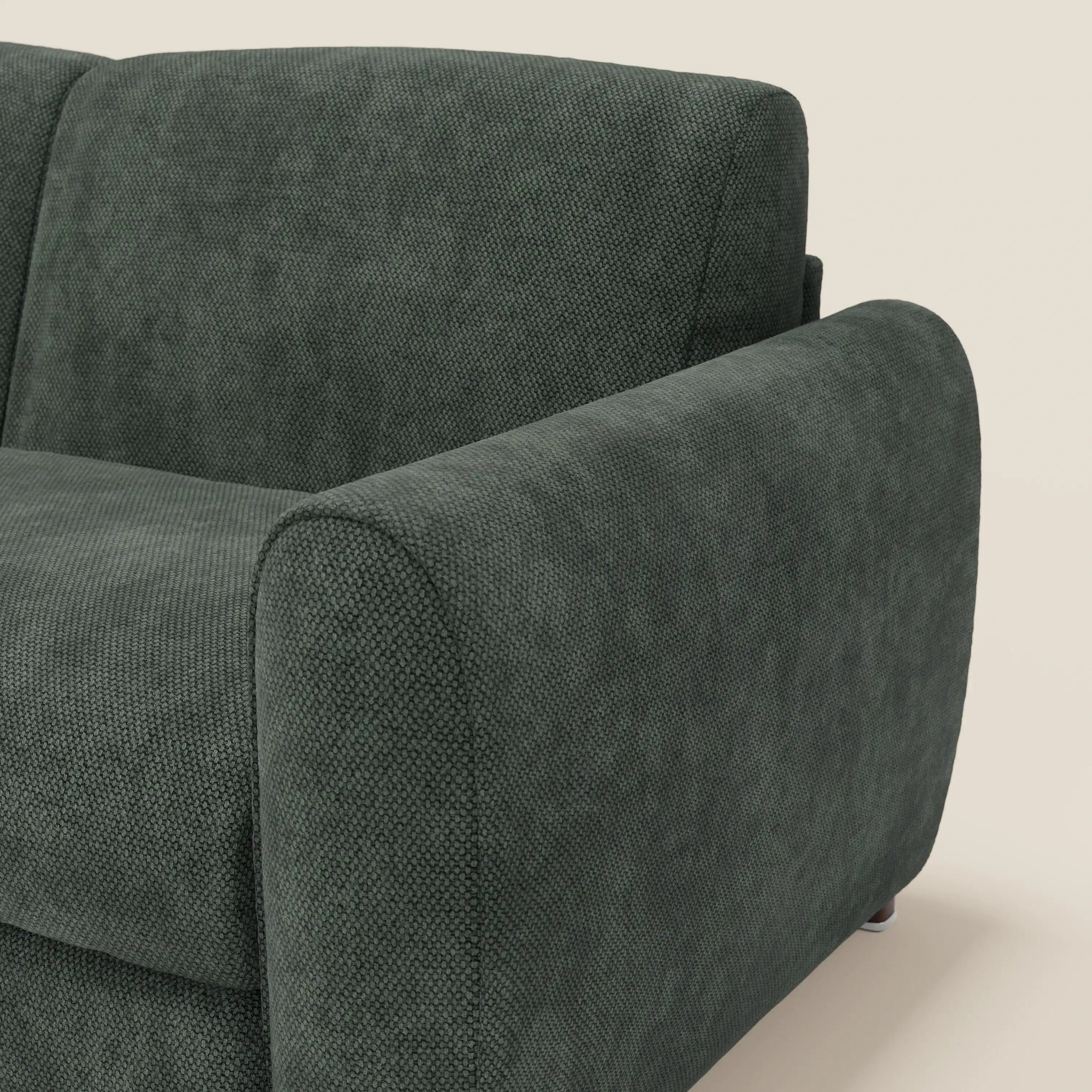 Primo piano del divano letto moderno Kaleo di Divani.Store in raffinato tessuto impermeabile T26 verde oliva, con ampio bracciolo, schienale e cuscino di seduta in feltro. Il design contemporaneo spicca su uno sfondo beige chiaro.