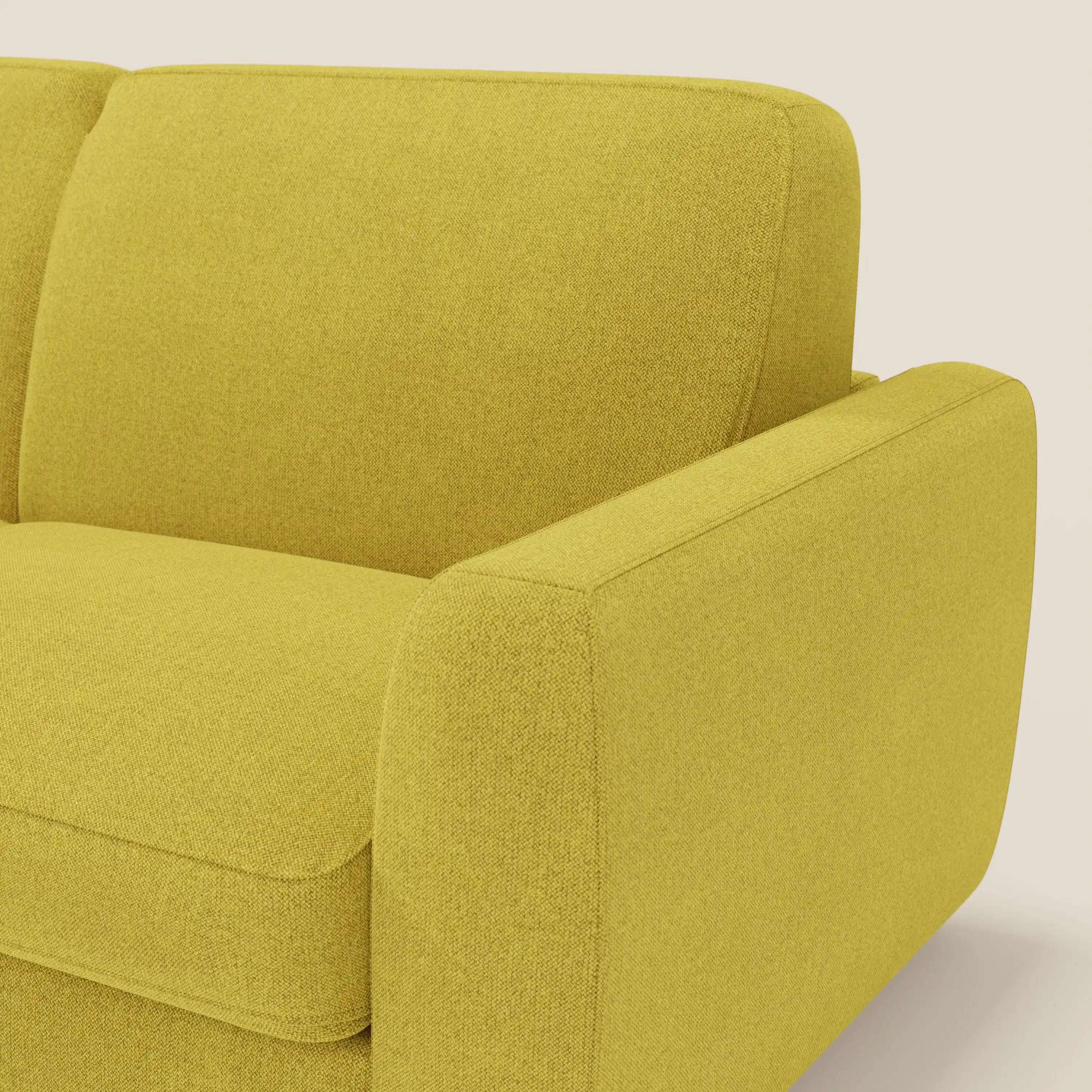 Primo piano del divano letto sfoderabile Leonida di Divani.Store, presentato in tessuto Smacchiabile T23 giallo sole. L'attenzione al bracciolo, al cuscino e allo schienale destro ne evidenzia la consistenza felpata e lo stile minimalista su uno sfondo chiaro.