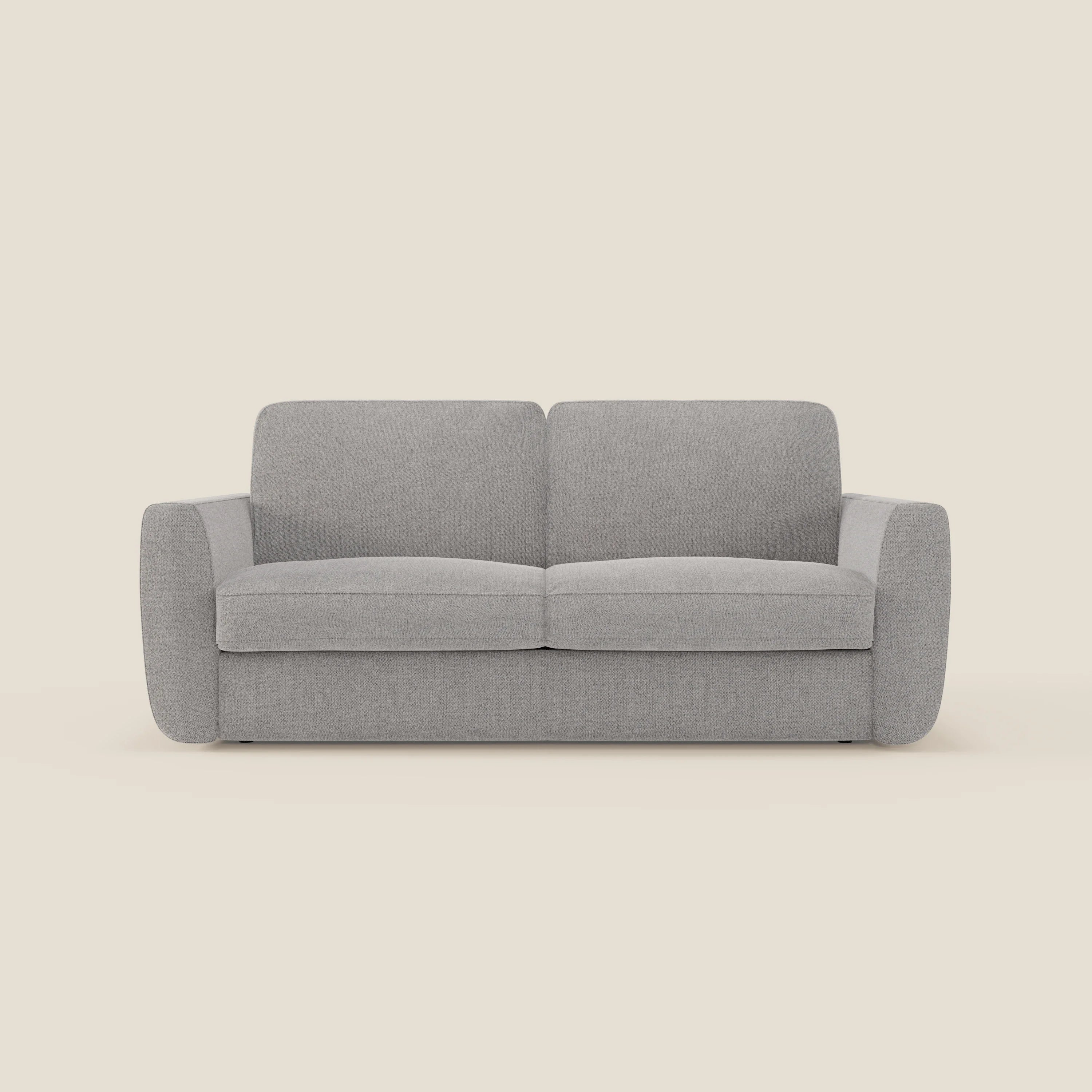 Il divano letto sfoderabile Leonida di Divani.Store in smacchiabile T23 grigio è caratterizzato da braccioli arrotondati, cuscini di schienale rettangolari e un design pulito e minimale senza gambe visibili, su uno sfondo beige chiaro.