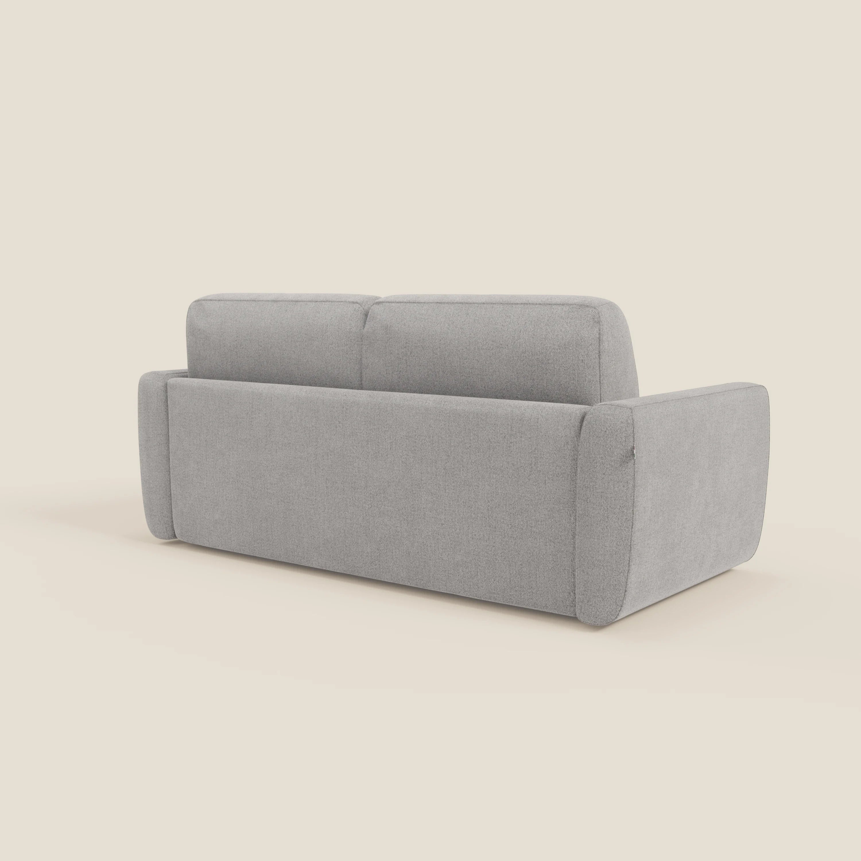 Il divano letto sfoderabile Leonida di Divani.Store è presentato in posizione angolare, con spessi braccioli imbottiti e un materasso H18 cm ad alta densità in tessuto Smacchiabile T23 grigio su uno sfondo beige chiaro.