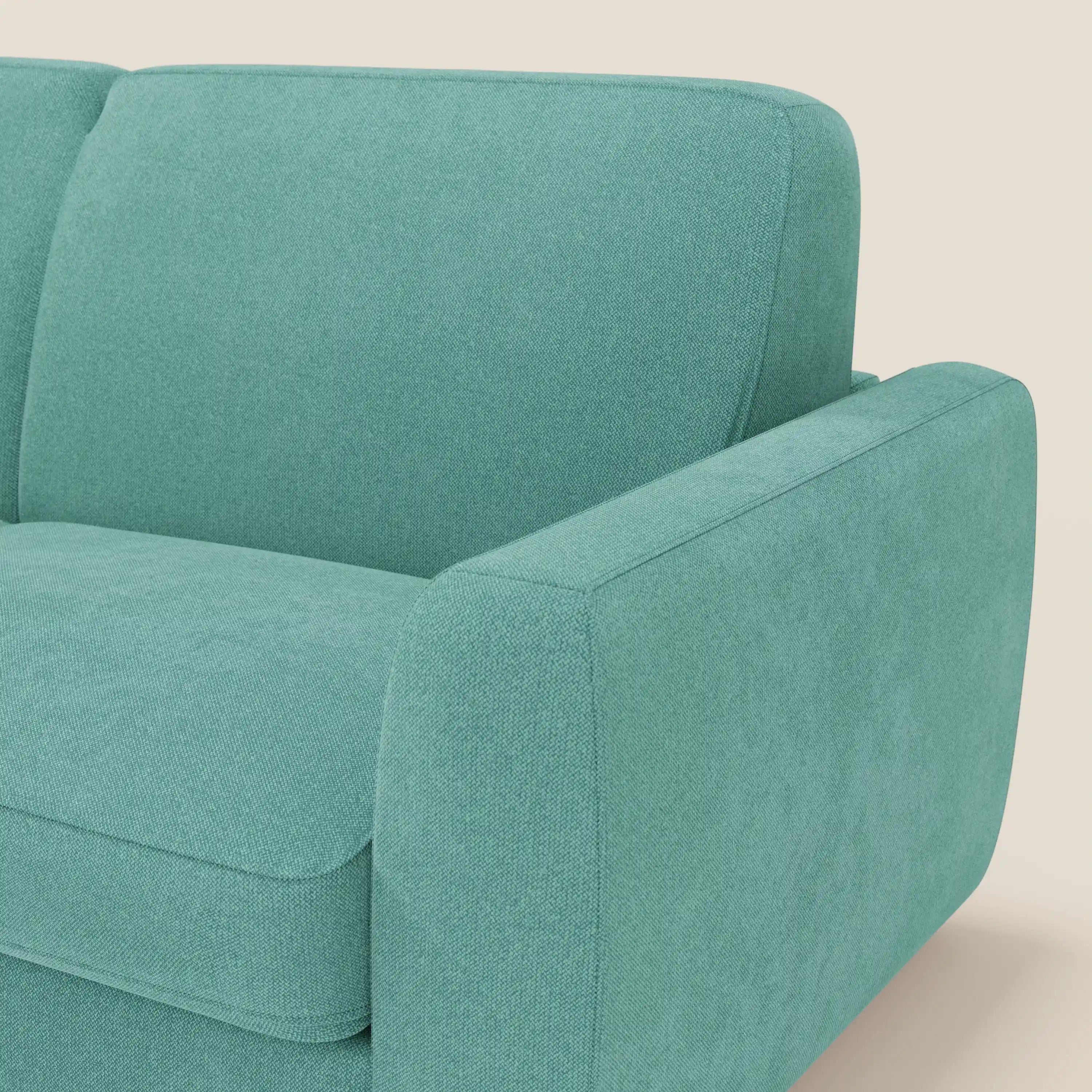 Primo piano del bracciolo e dello schienale destro del divano letto sfoderabile Leonida di Divani.Store in tessuto Smacchiabile T23 verde acqua. Lo sfondo bianco sporco mette in risalto l'imbottitura strutturata, le linee minimaliste e il meccanismo in acciaio rinforzato.