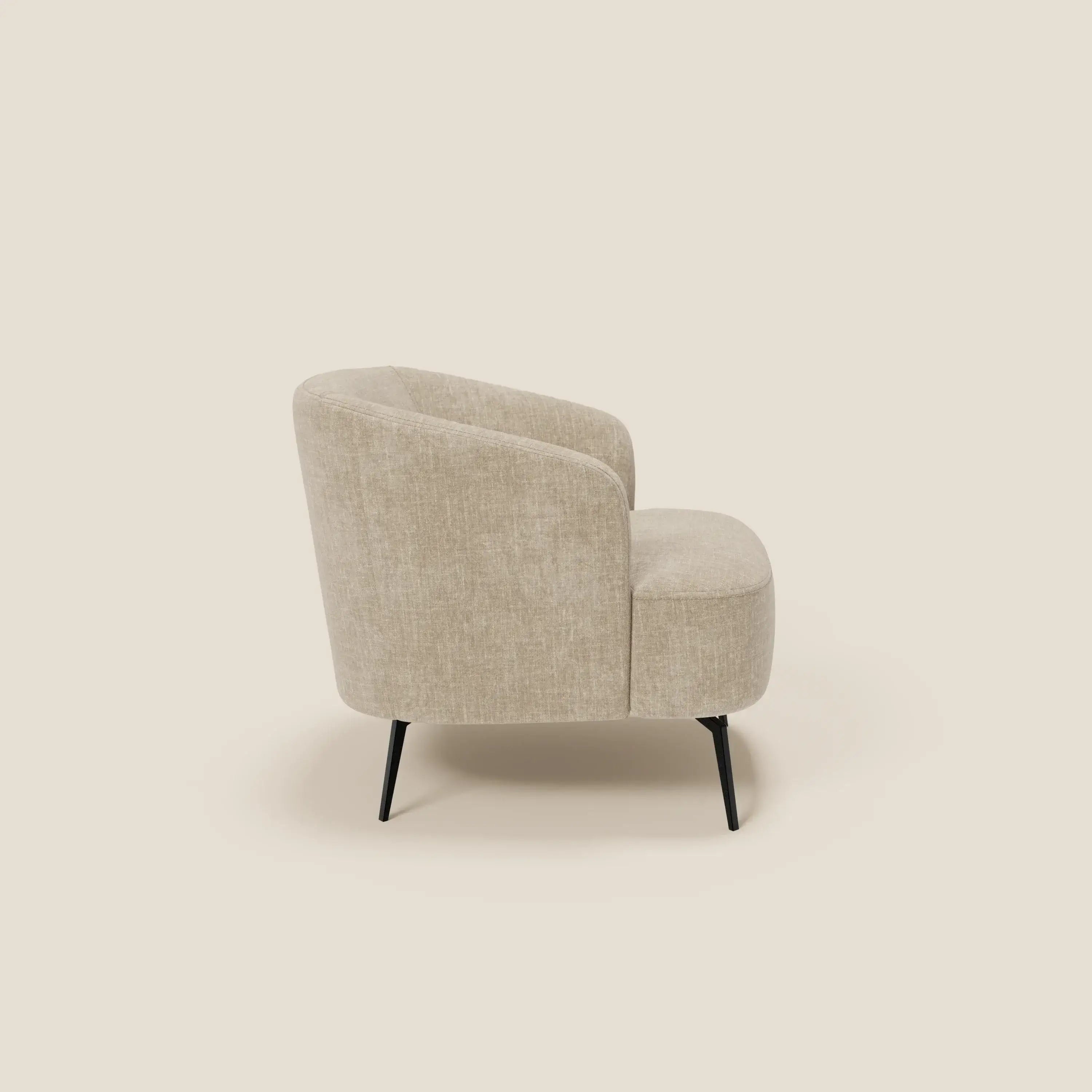 La poltroncina Renoa dall'eleganza moderna in tessuto smacchiabile T24 beige di Divani.Store è raffigurata di profilo su uno sfondo crema, con bordi curvi, seduta imbottita e sottili gambe in metallo nero per un look contemporaneo.