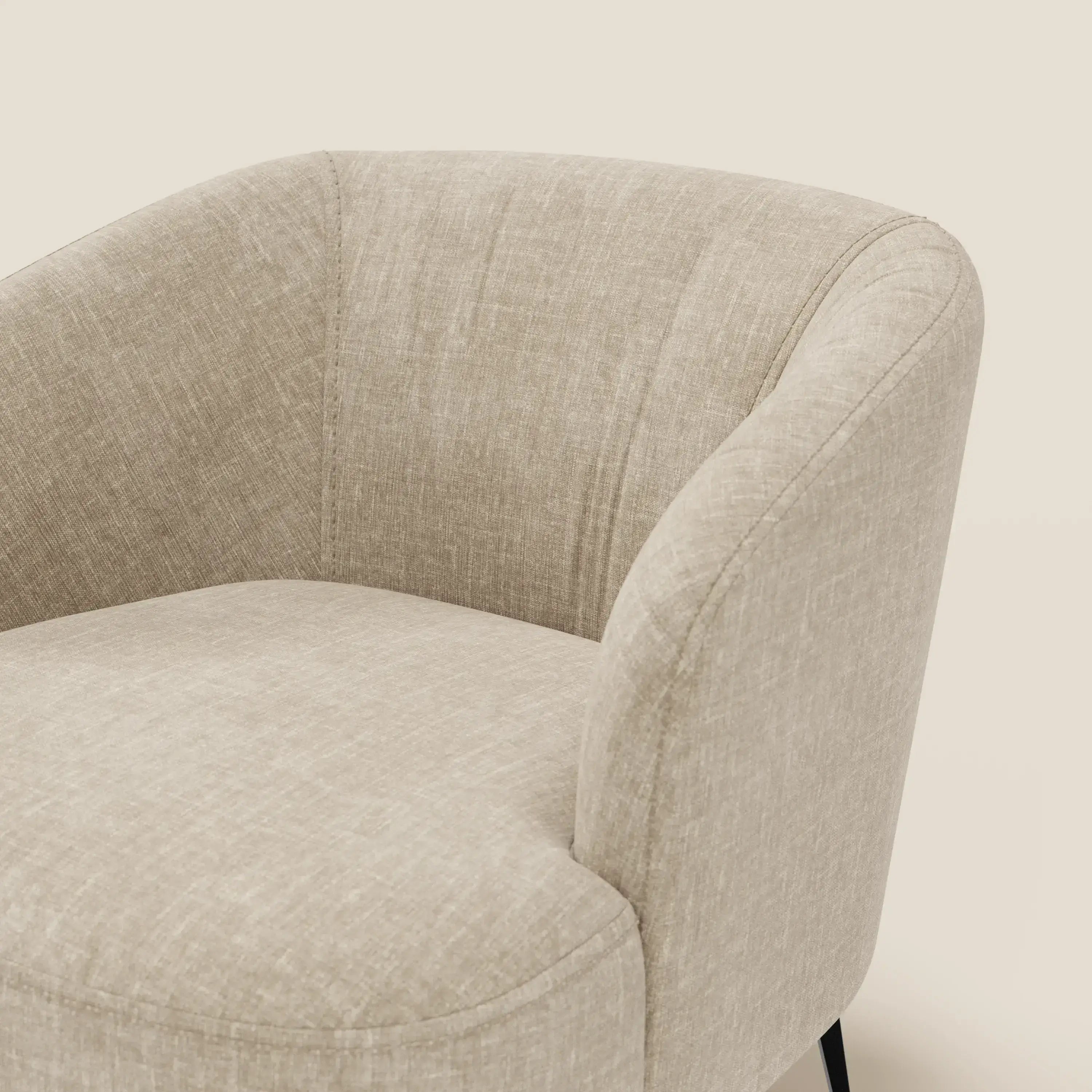 Primo piano della poltroncina Renoa dall'eleganza moderna in tessuto smacchiabile T24 beige di Divani.Store, caratterizzata da uno schienale curvo, sottili cuciture e sottili gambe in metallo nero su uno sfondo bianco sporco.