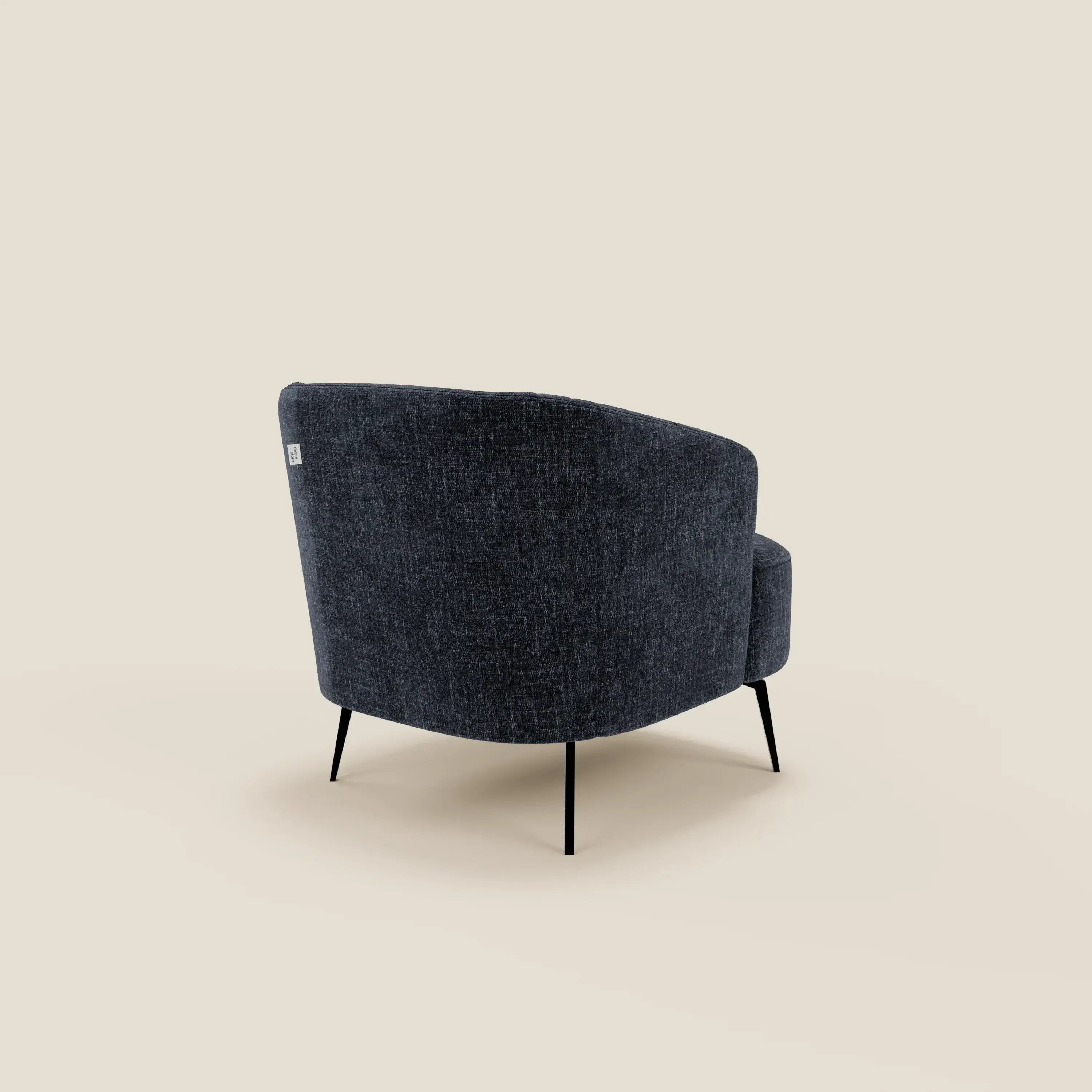 La poltroncina Renoa di Divani.Store, rivestita in tessuto smacchiabile T24 blu notte, presenta uno schienale curvo e sottili gambe in metallo nero. Presentata dal retro in posizione obliqua su uno sfondo beige chiaro.