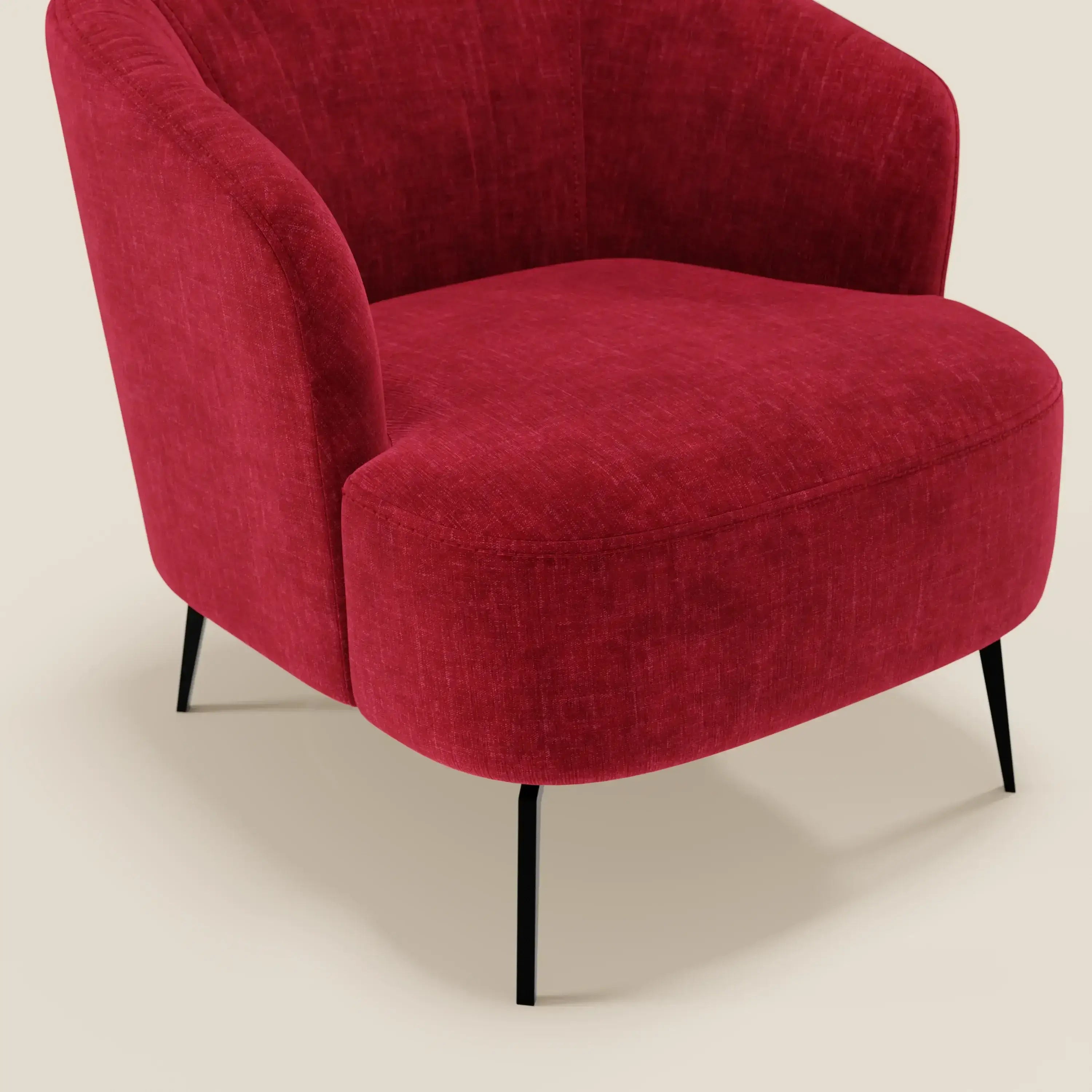 La poltroncina Renoa di Divani.Store è caratterizzata da schienale e seduta curvi in tessuto smacchiabile T24 rosso bordeaux, sottili gambe in metallo nero e un design moderno che spicca su uno sfondo beige.
