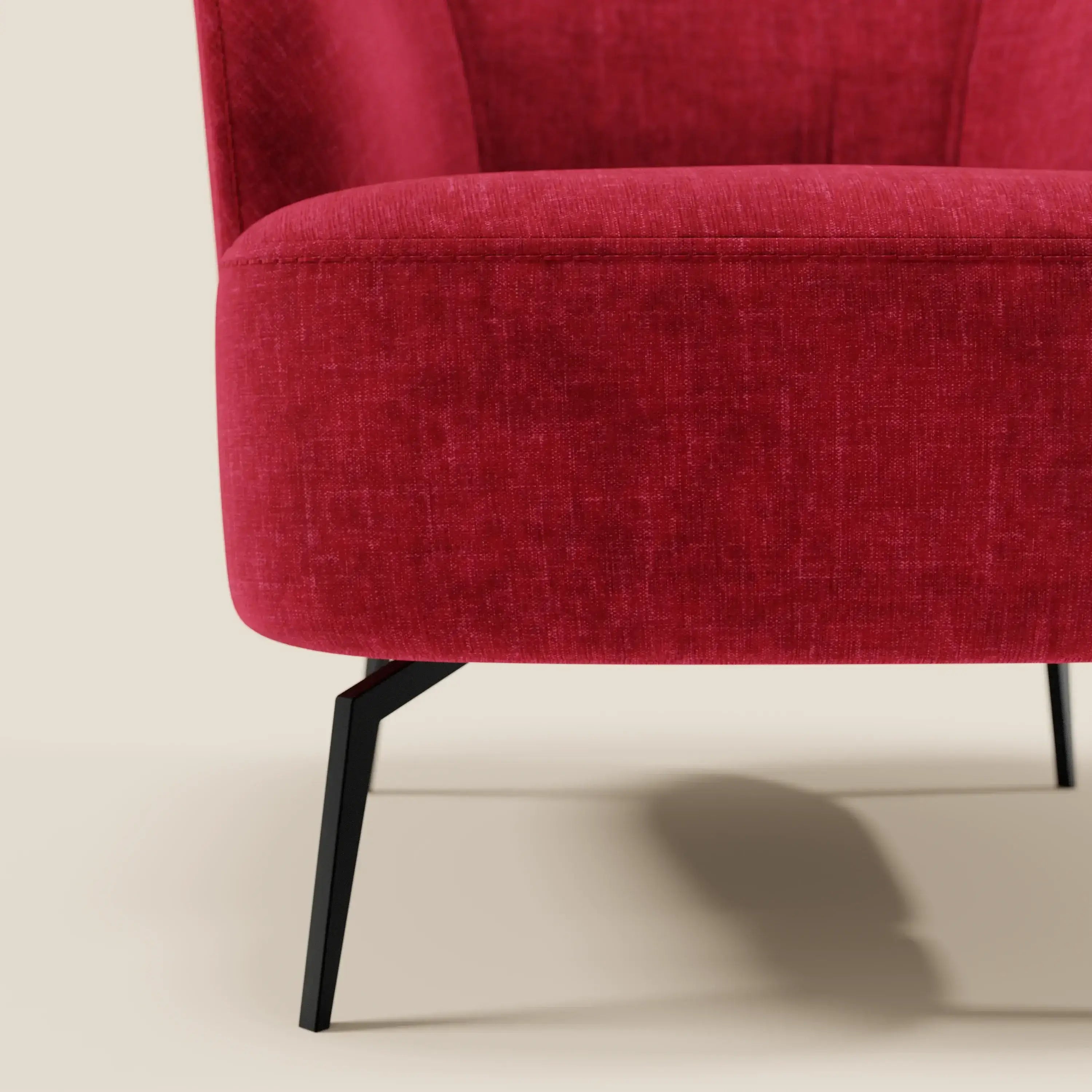 Primo piano della poltroncina Renoa di Divani.Store, dall'elegante design moderno in tessuto antimacchia T24 rosso bordeaux, con schienale e seduta ergonomici e curvi su gambe angolate in metallo nero; solo la metà inferiore appare su uno sfondo beige.