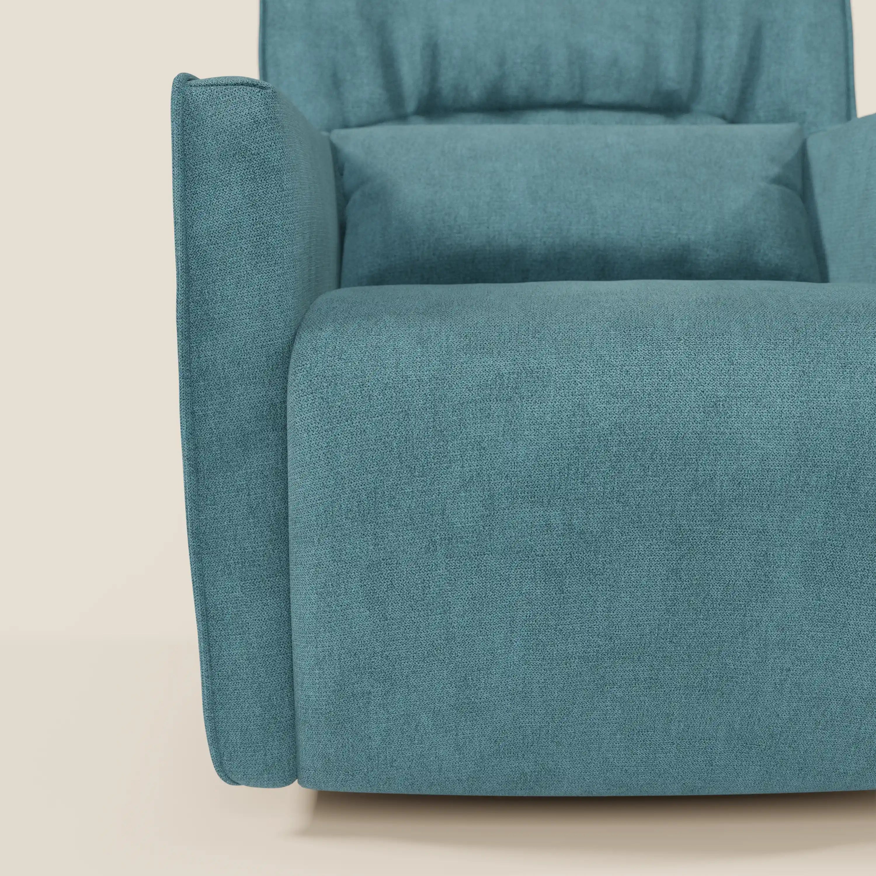Un primo piano di Tulla Poltrona girevole in tessuto impermeabile T02 azzurro di Divani.Store ne mostra gli spessi braccioli e lo schienale imbottito. Il morbido tessuto verde acqua di questa poltrona moderna offre comfort e si appoggia su una superficie chiara con uno sfondo bianco sporco.