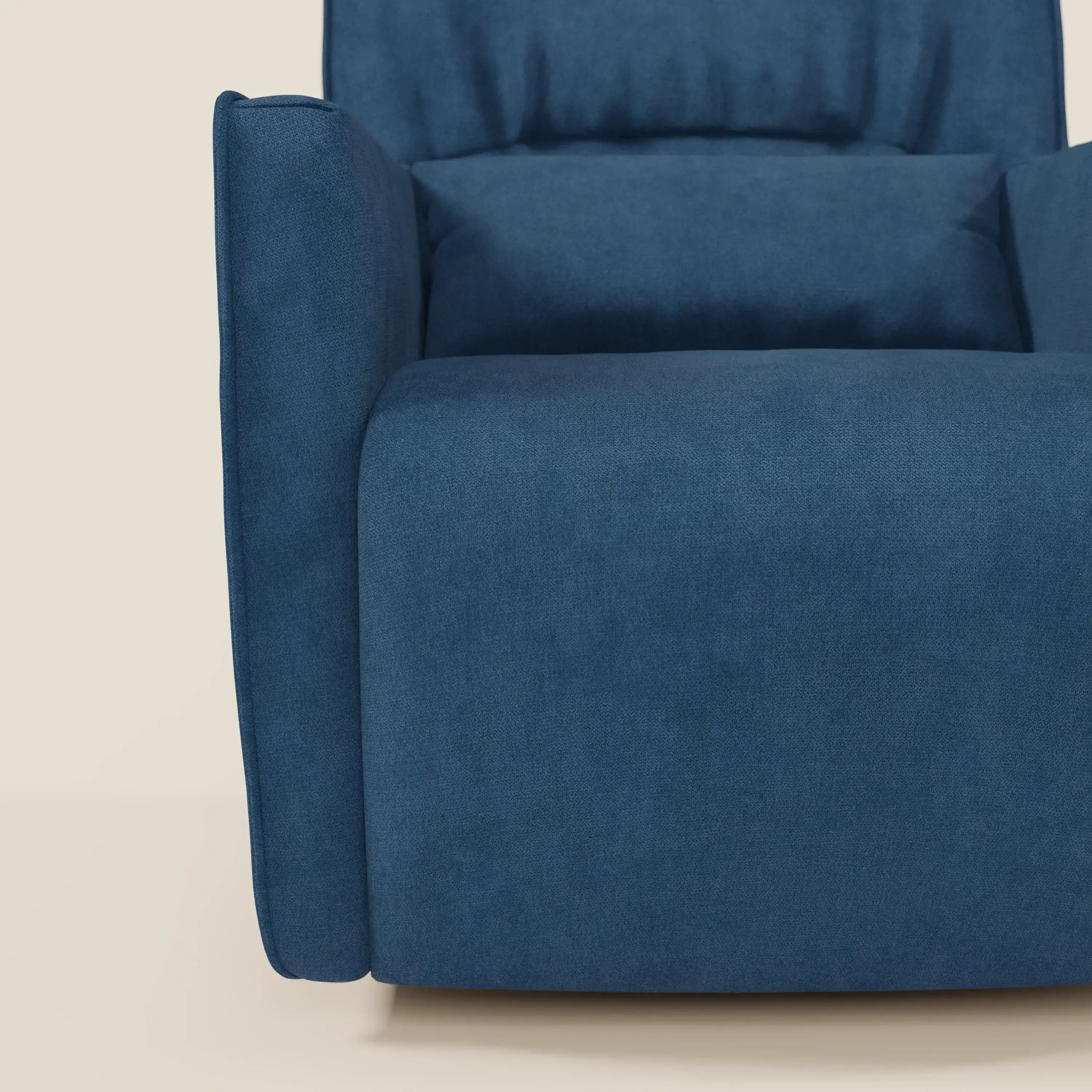 Un primo piano di Tulla Poltrona girevole in tessuto impermeabile T02 blu di Divani.Store mostra la sua seduta morbida e squadrata, il bracciolo e lo schienale di colore blu intenso su uno sfondo beige chiaro.