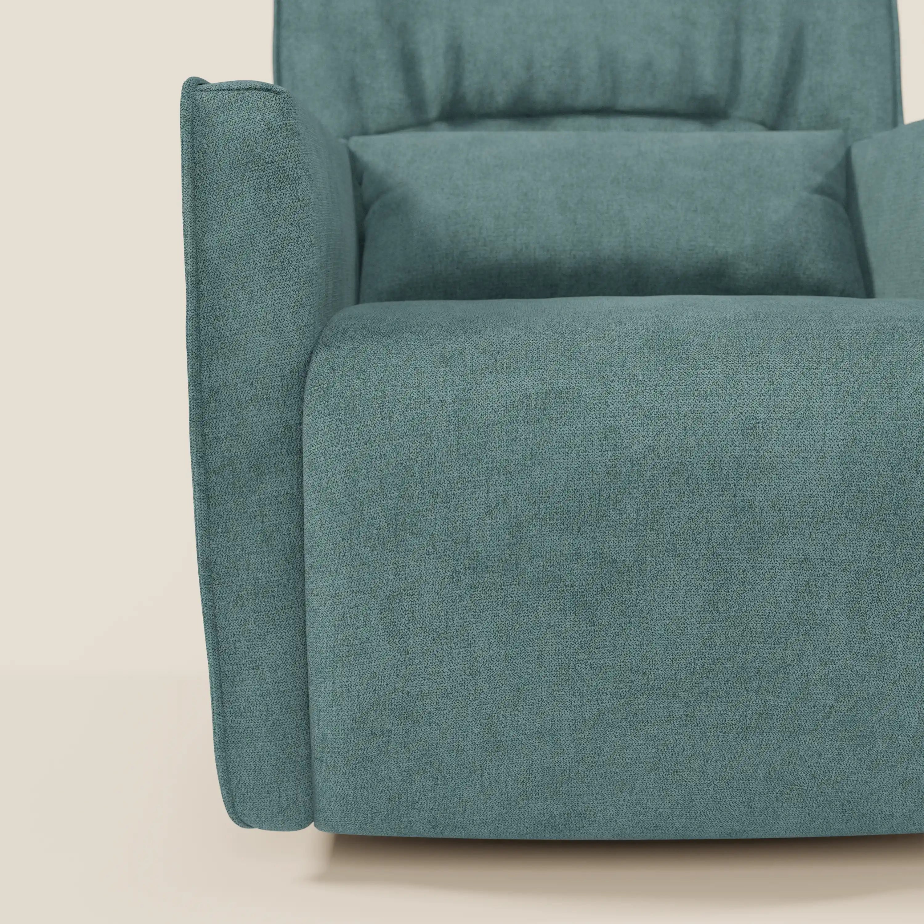 Un primo piano di Tulla Poltrona girevole in tessuto impermeabile T02 petrolio di Divani.Store mostra l'ampio bracciolo, la seduta morbida e lo schienale imbottito in tessuto verde acqua su uno sfondo beige.