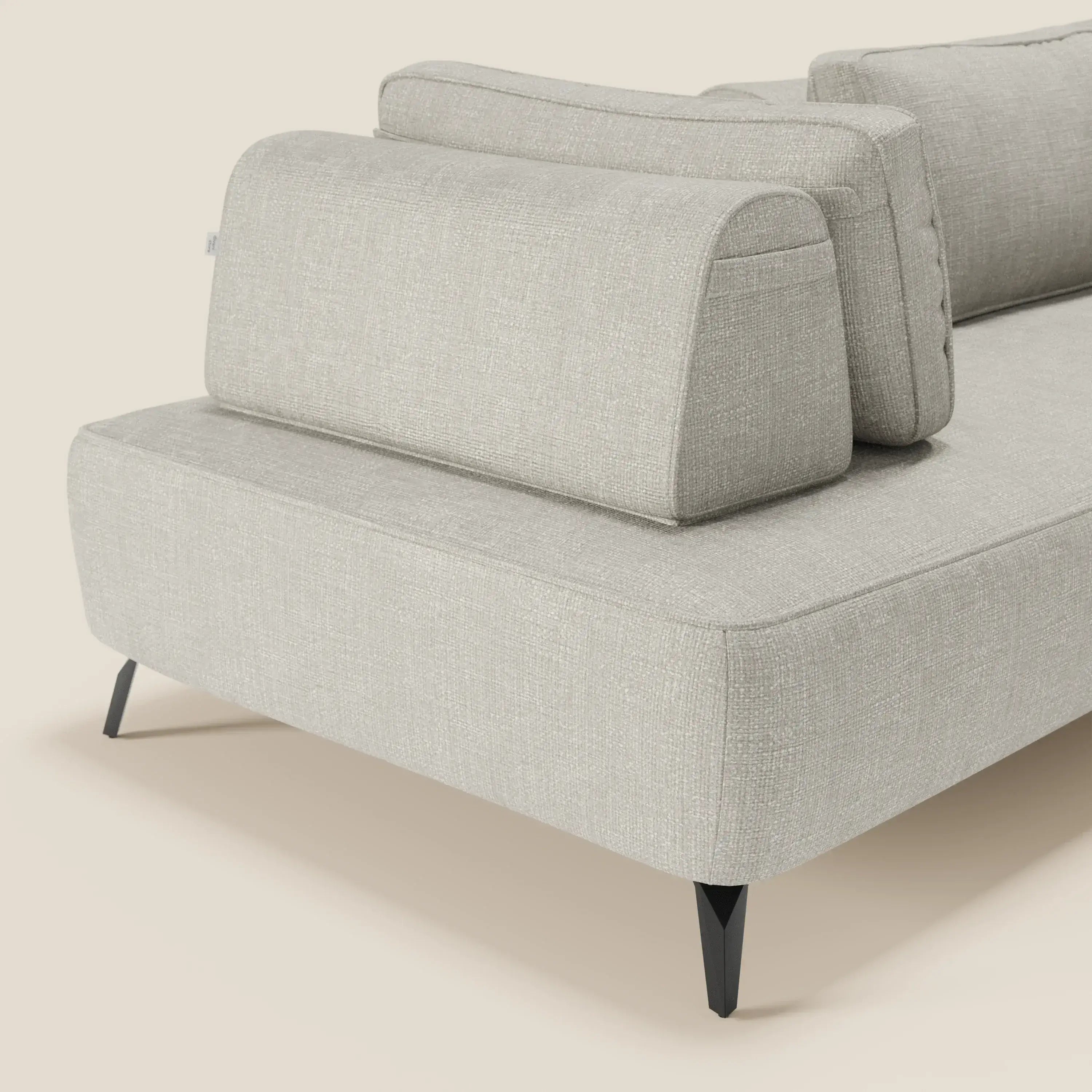 Un primo piano del divano modulare Volta con schienali mobili in raffinato tessuto ciniglia T06 grigio chiaro di Divani.Store, con linee pulite, gambe nere angolate e un look minimalista e contemporaneo su uno sfondo neutro.